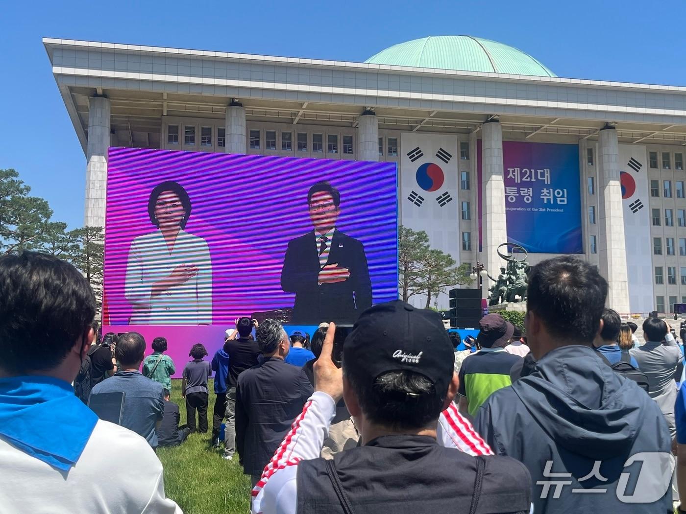 본문 이미지 - 이재명 21대 대통령 취임식이 열리는 4일 오전 서울 여의도 국회의사당 잔디광장에 시민들이 모여 취임 선서를 지켜보고 있다. / 뉴스1 김종훈 기자