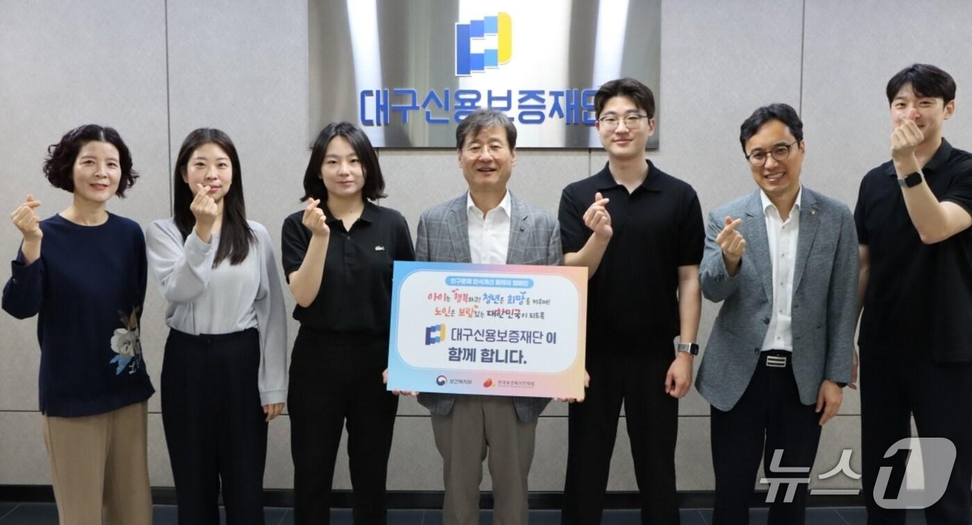 '인구문제 인식개선 릴레이 캠페인'에 동참한 박진우 대구신용보증재단 이사장(가운데)이 손가락 하트를 만들어 보이는 직원들과 기념사진을 찍고 있다.(대구신보 제공. 재판매 및 DB 금지)