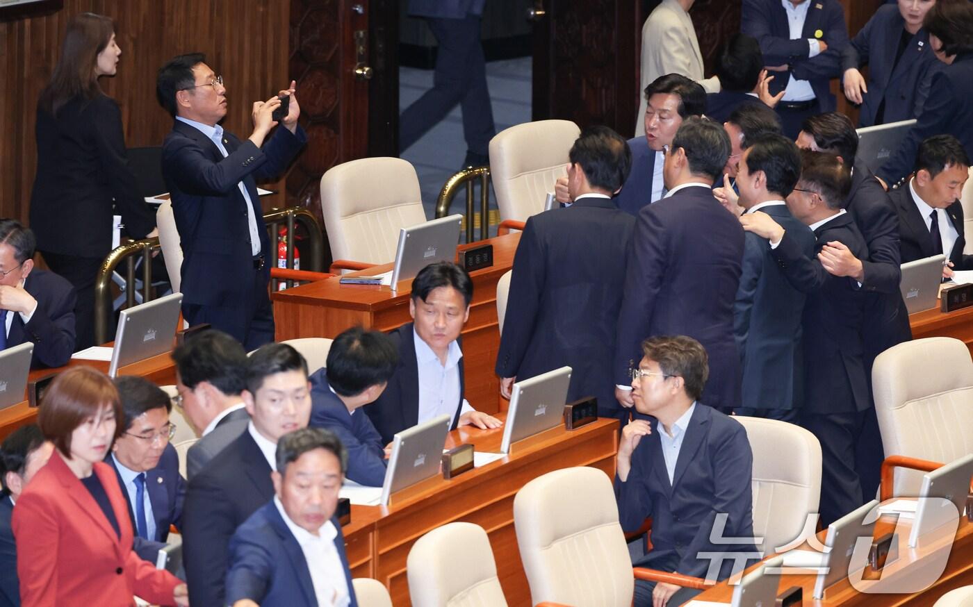 더불어민주당 의원들이 5일 오후 서울 여의도 국회 본회의장에서 기념 촬영하는 가운데 국민의힘 의원들이 입장하고 있다. 2025.6.5/뉴스1 ⓒ News1 안은나 기자