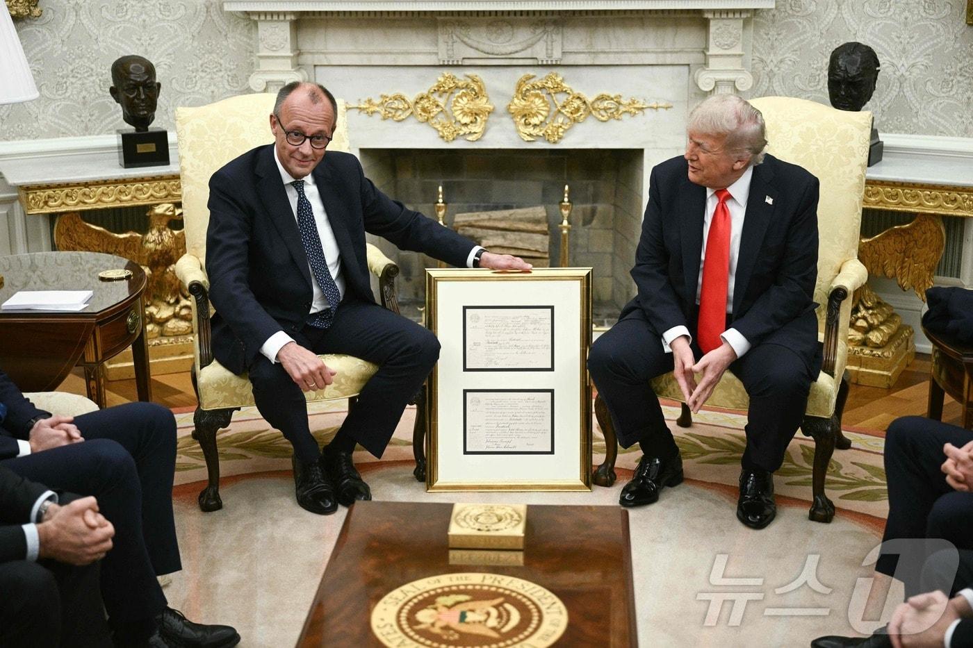 프리드리히 메르츠 독일 총리가 5일(현지시간) 워싱턴 백악관에서 도널드 트럼프 미국 대통령과의 정상회담 도중에 1869년 독일에서 태어난 트럼프 대통령 조부의 출생 증명서 사본을 선물로 전달하고 있다. 2025.06.05 ⓒ AFP=뉴스1 ⓒ News1 최종일 선임기자