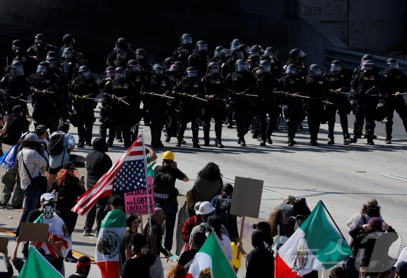 8일&#40;현지시간&#41; 미국 캘리포니아주 로스앤젤레스&#40;LA&#41;에서 도널드 트럼프 행정부의 불법이민 단속에 항의하는 시위대가 경찰 병력과 대치하고 있다. 트럼프 대통령은 시위 진압을 위해 7일 이례적으로 주방위군 2000명 투입을 명령하면서 시위 양상이 더욱 격화되고 있다. 2025.06.08 ⓒ 로이터=뉴스1 ⓒ News1 김지완 기자