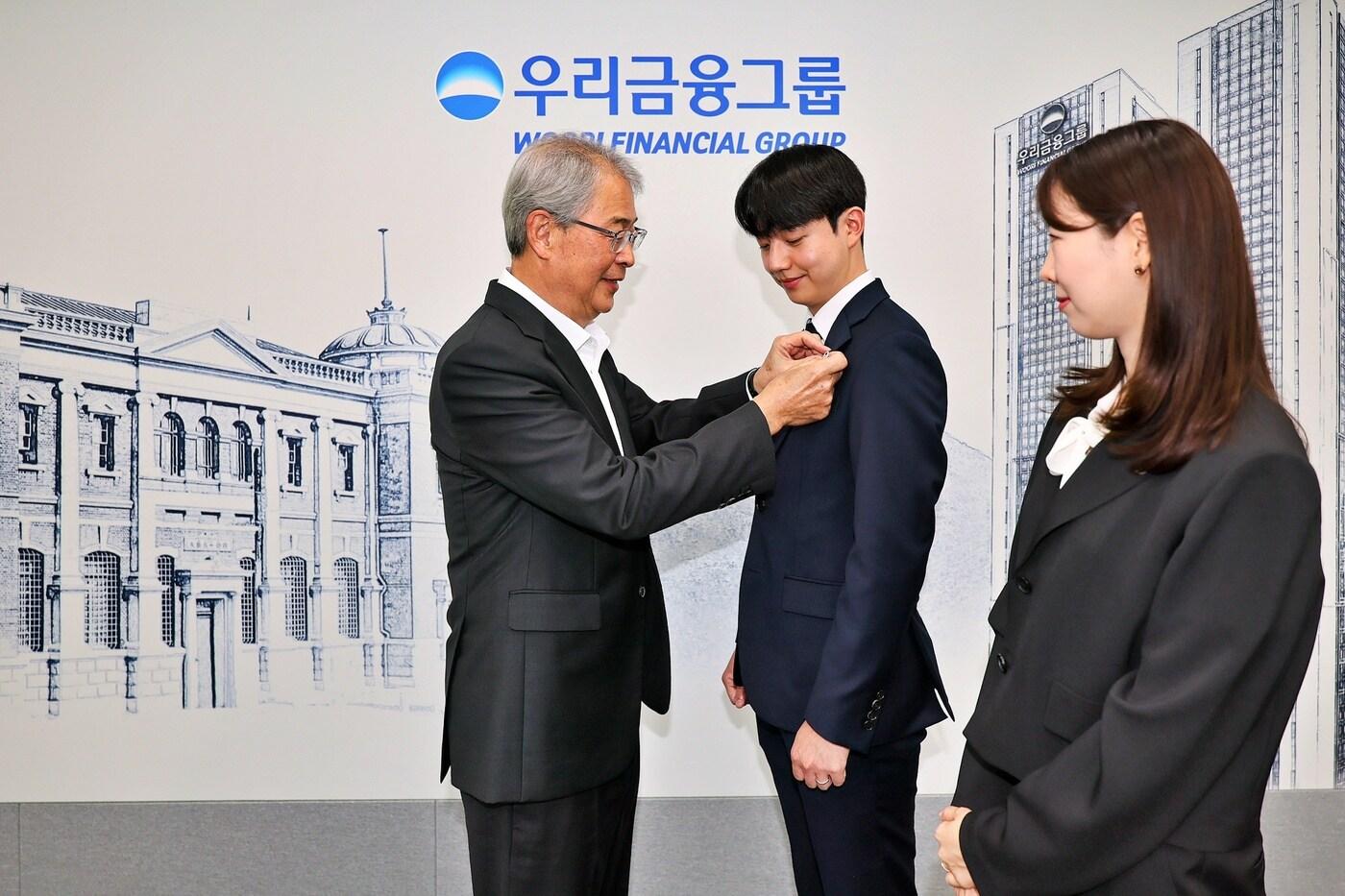 우리금융그룹 임종룡 회장이 그룹의 새 가족이 된 동양생명·ABL생명 직원에게 디지털 선도의 의미가 담긴 새로운 그룹 보조휘장을 달아주고 있다.&#40;우리금융그룹 제공&#41;