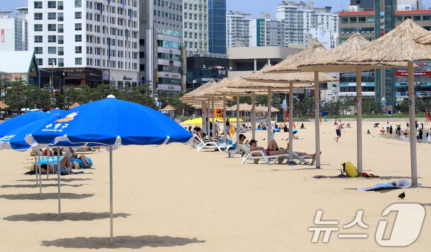 무더위가 기승을 부린 1일 개장한 부산 수영구 광안리해수욕장을 찾은 관광객들이 파라솔 아래에서 휴식을 취하고 있다.2025.7.1/뉴스1 ⓒ News1 윤일지 기자