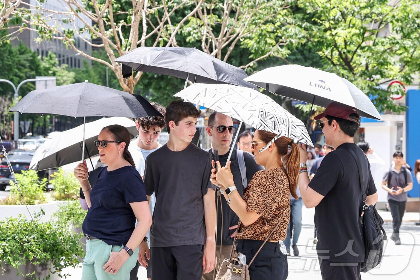 전국이 고온다습한 기후 속에 서울 지역 낮 최고기온이 30도까지 올라 찜통더위가 찾아온 1일 서울 종로구 광화문 네거리에서 외국인 관광객들이 양산 아래 모여 따가운 햇빛을 피하고 있다. 2025.7.1/뉴스1 ⓒ News1 민경석 기자