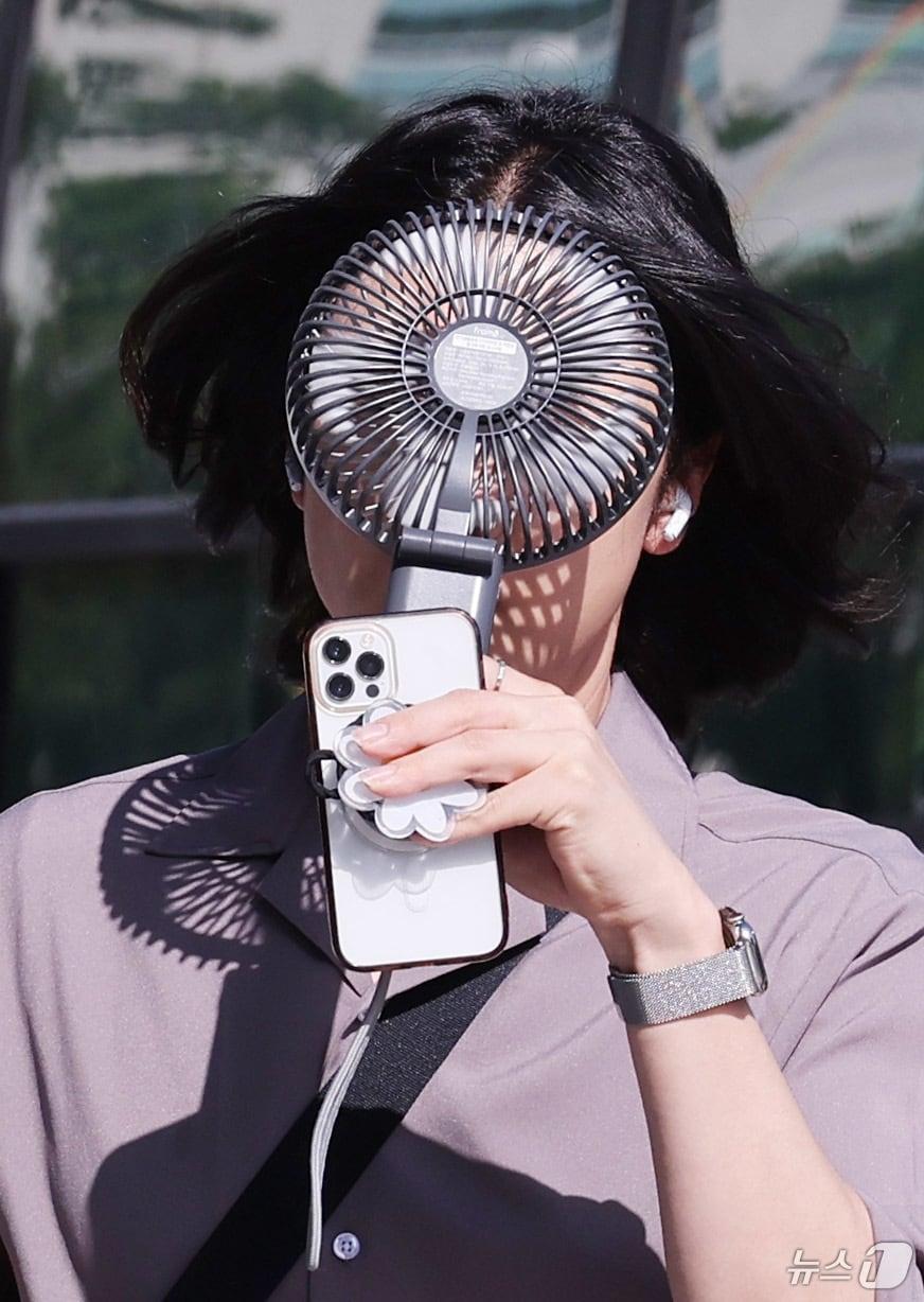 본문 이미지 - 한 시민이 손선풍기를 얼굴에 대며 출근하고 있다. &#40;사진은 기사 내용과 무관함&#41; / 뉴스1 ⓒ News1