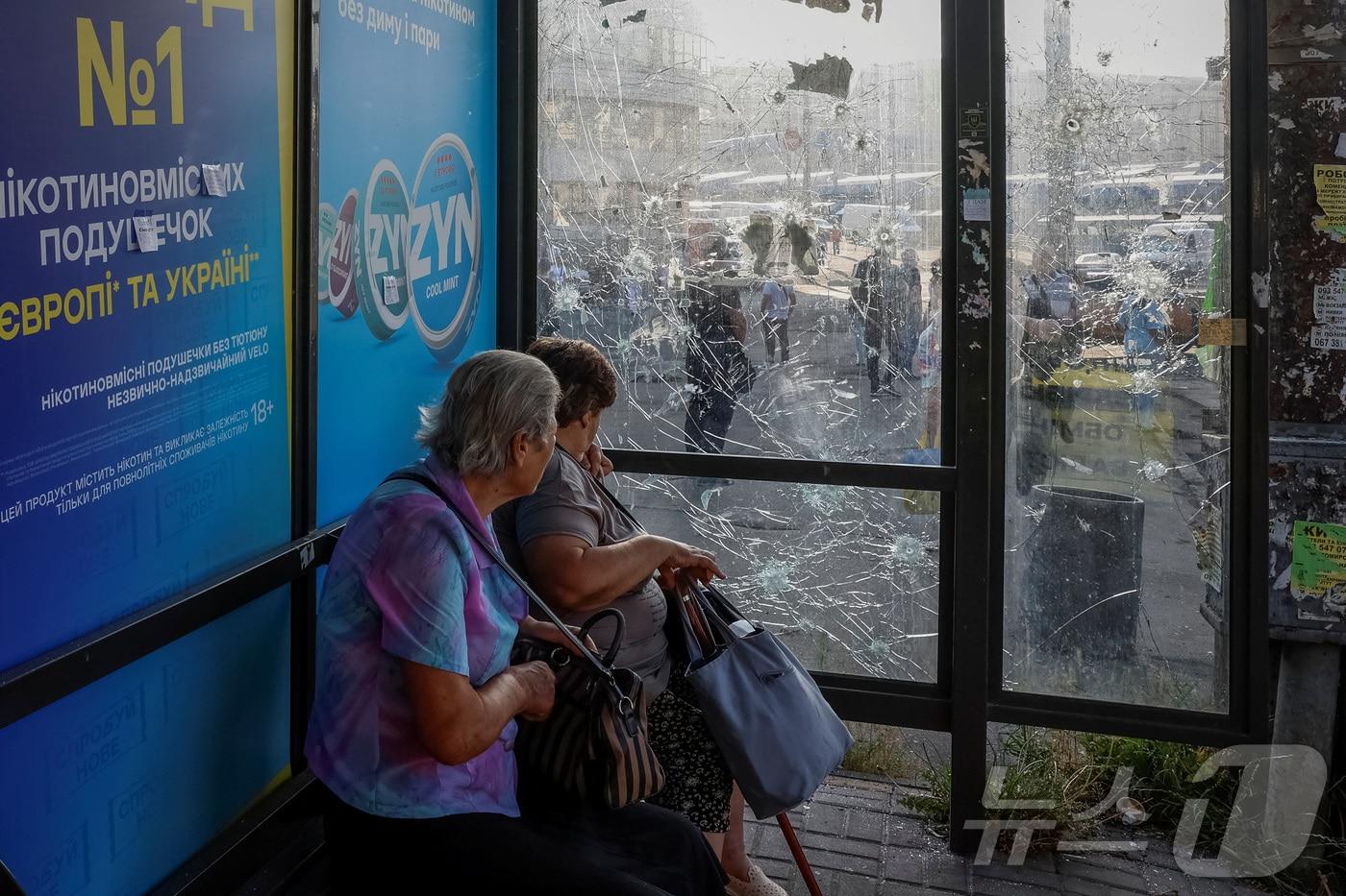  우크라이나 키이우에서 러시아의 드론 공격으로 유리창이 깨친 버스 정류장에 여성들이 앉아 있다. ⓒ 로이터=뉴스1 ⓒ News1 최종일 선임기자