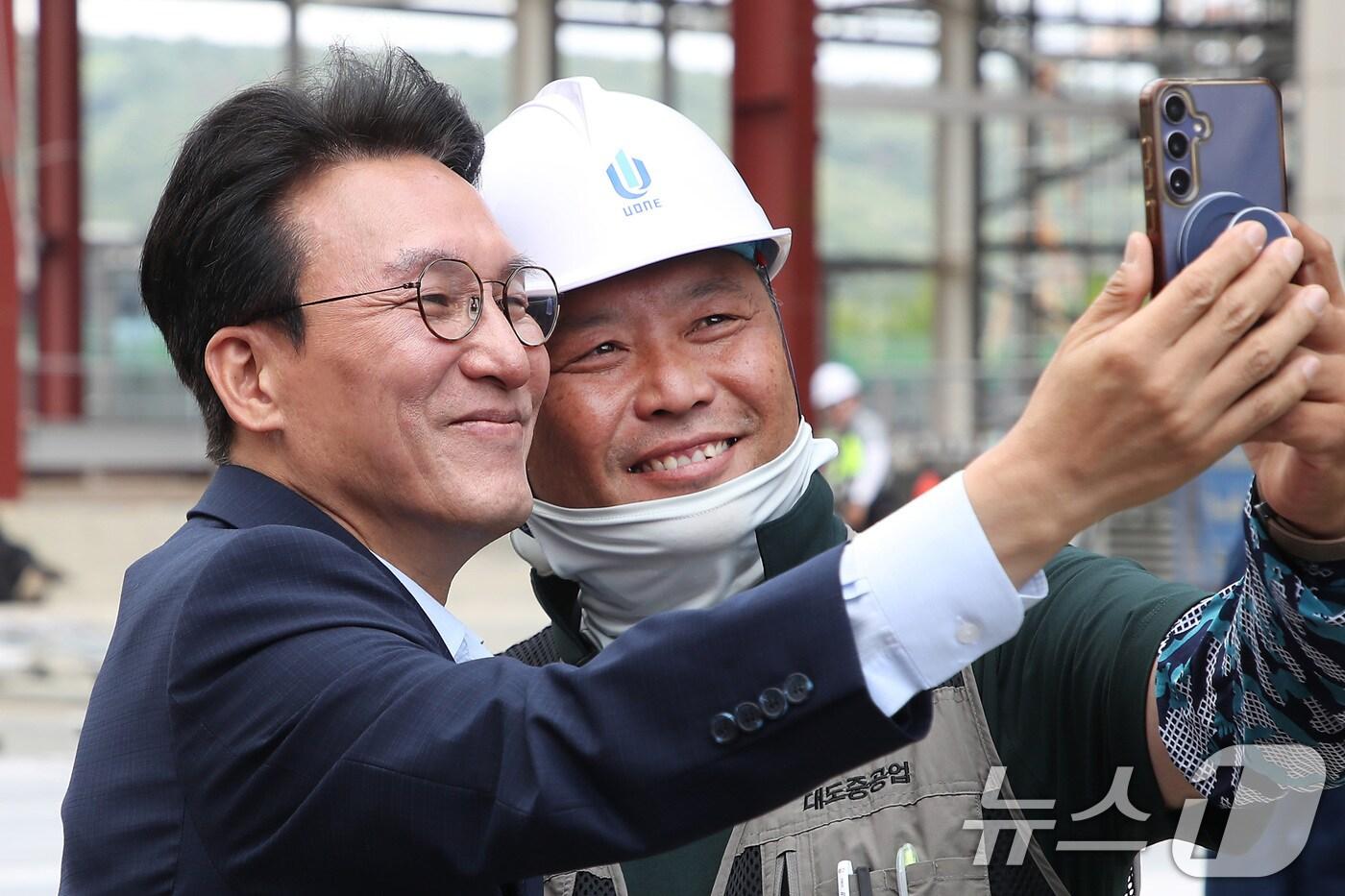 김민석 국무총리가 11일 오전 경북 경주화백컨벤션센터를 찾아 APEC 정상회의 미디어센터 건립 현장에서 무더위와 싸우며 일하는 근로자들을 격려한 뒤 이들의 요청에 기념촬영하고 있다. 2025.7.11/뉴스1 ⓒ News1 공정식 기자