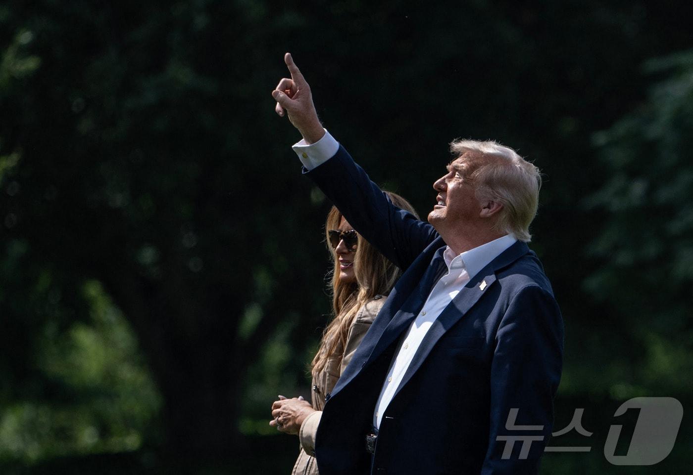 도널드 트럼프 미국 대통령이 11일&#40;현지시간&#41; 워싱턴DC에서 영부인 멜라니아 트럼프와 함께 &#39;마린 원&#39;&#40;미 대통령 전용헬기&#41;에 탑승하기 위해 걸어가면서 백악관 남쪽 잔디밭의 새 성조기를 가리키고 있다. 2025.07.11 ⓒ AFP=뉴스1 ⓒ News1 류정민 특파원