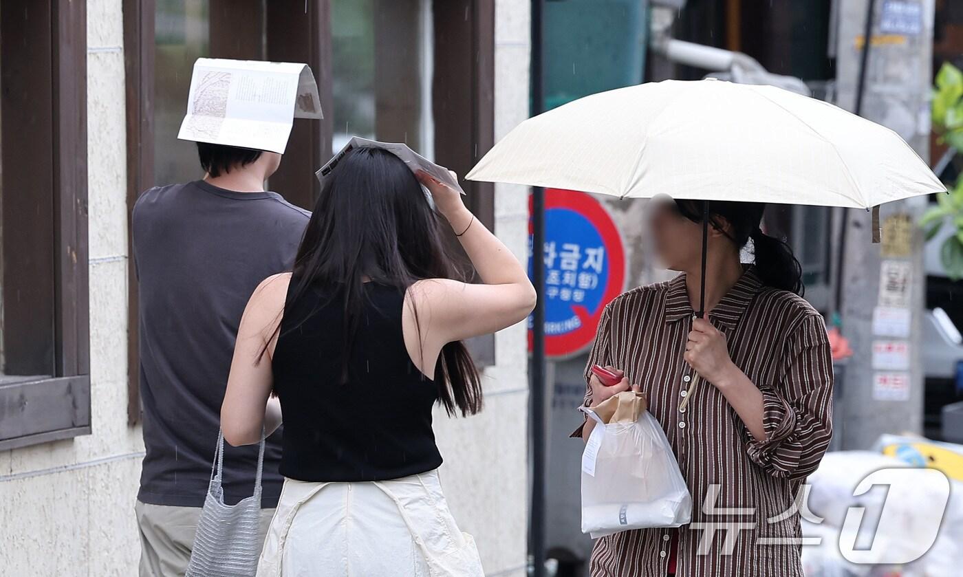 13일 서울 종로구 거리에서 시민들이 팜플렛으로 머리를 가린 채 거리를 거닐고 있다. 2025.7.13/뉴스1 ⓒ News1 김성진 기자