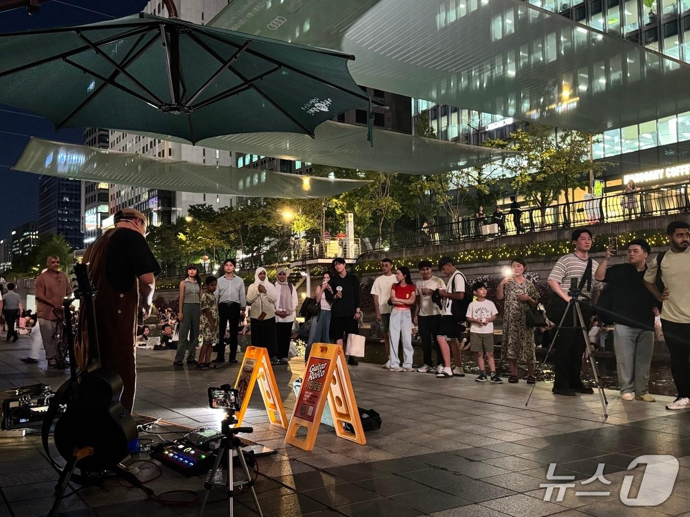 본문 이미지 - 11일 오후 청계천 모전교 일대에서 이뤄진 길거리 공연을 시민들이 모여 관람하고 있다. 2025.07.14/뉴스1 ⓒ 뉴스1 권준언 기자