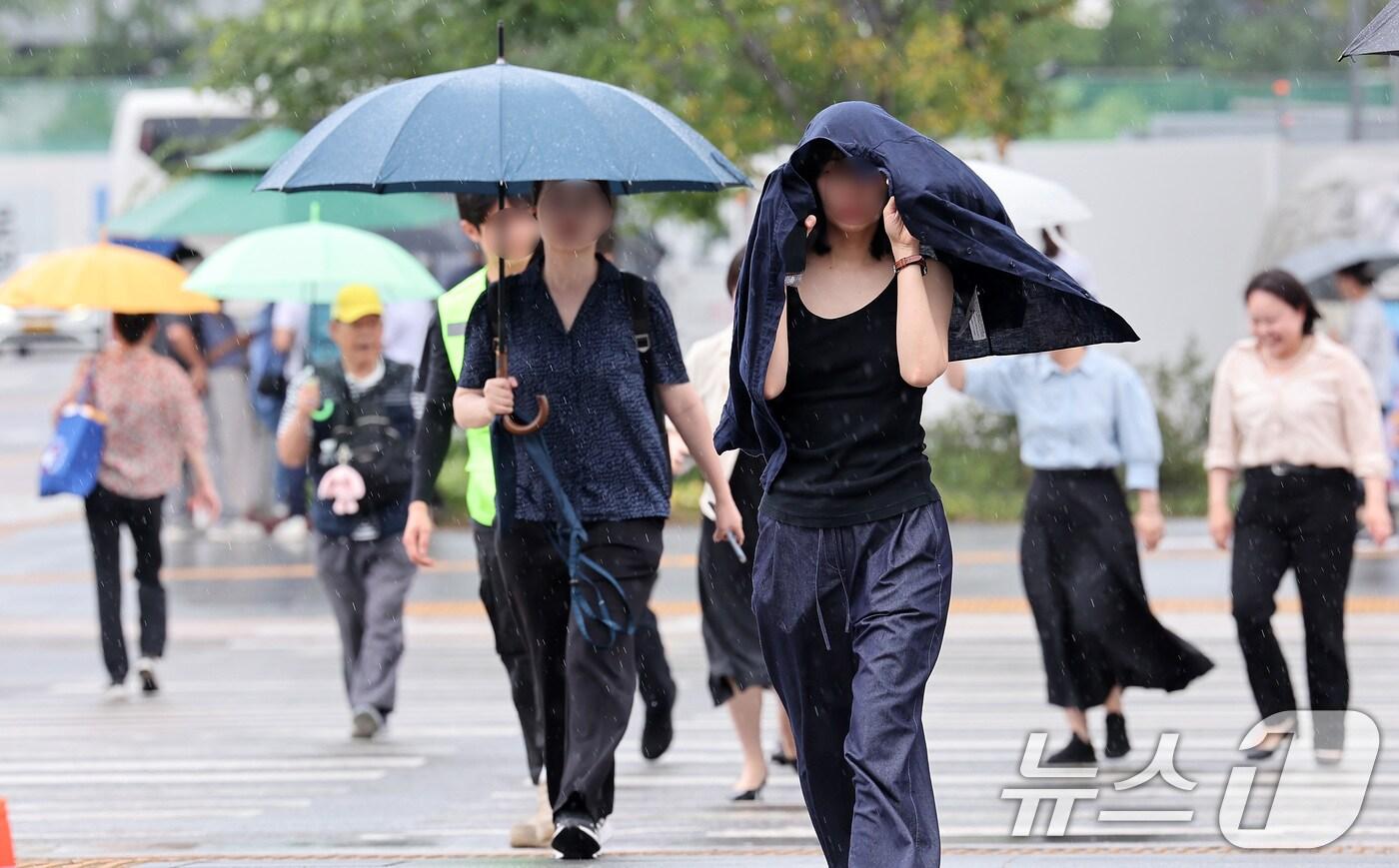 전국 대부분 지역에 비가 내린 14일 서울 종로구 광화문광장에서 우산을 준비하지 못한 한 시민이 겉옷을 두르고 발걸음을 옮기고 있다. 2025.7.14/뉴스1 ⓒ News1 김성진 기자