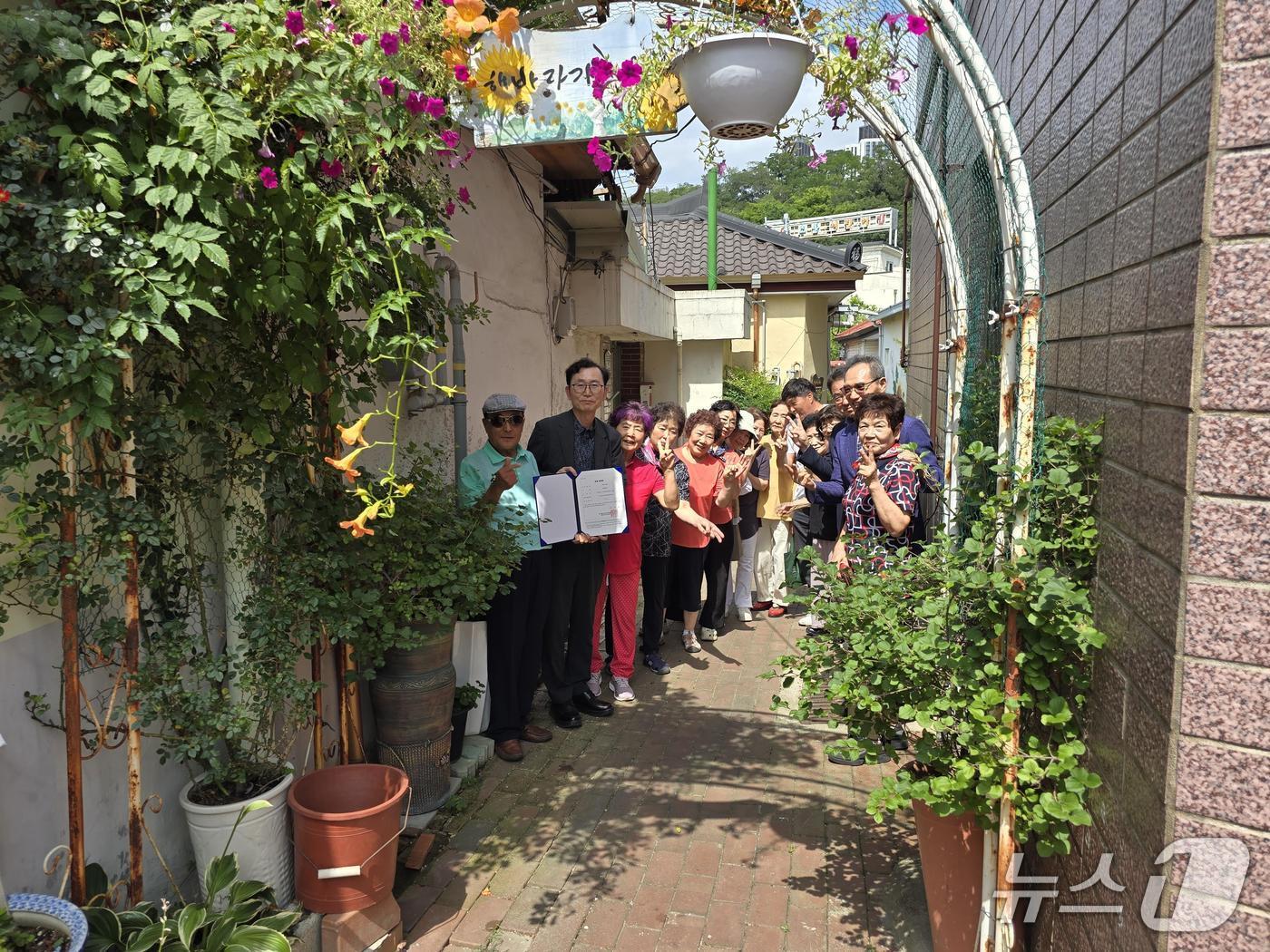 본문 이미지 - 대구 서구 소재 달성토성마을 골목정원이 대구시 1호 공동체 정원으로 지정돼 주민들이 단체 사진을 촬영하고 있다.(대구 서구 제공.재판매 및 DB 금지)