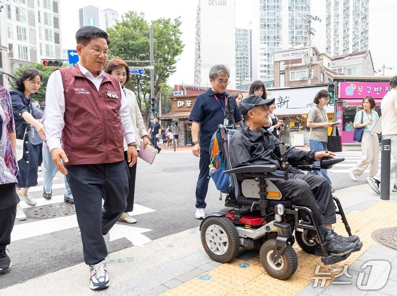 본문 이미지 - 박강수 마포구청장이 휠체어를 탄 주민과 함께 새로 조성된 무장애길을 걷고 있다.(마포구 제공)