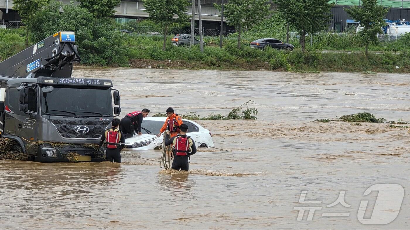 밤사이 쏟아진 집중폭우로 침수 피해가 발생한 17일 충남 아산시 배방읍 곡교천변에서 소방대원들이 불어난 빗물에 쓰러진 시설물과 침수차량을 살펴보고 있다. 2025.7.17/뉴스1 ⓒ News1 이시우 기자