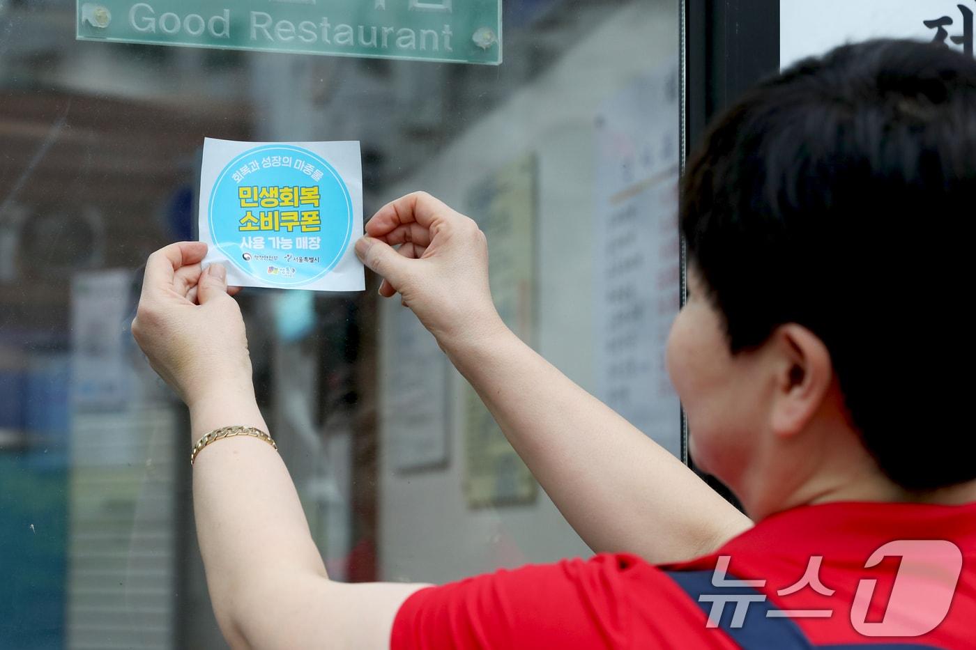 서울 성동구의 한 가게에서 '민생회복 소비쿠폰 사용 가능 매장' 스티커를 부착하고 있다. (성동구 제공. 재판매 및 DB 금지) 2025.7.17/뉴스1