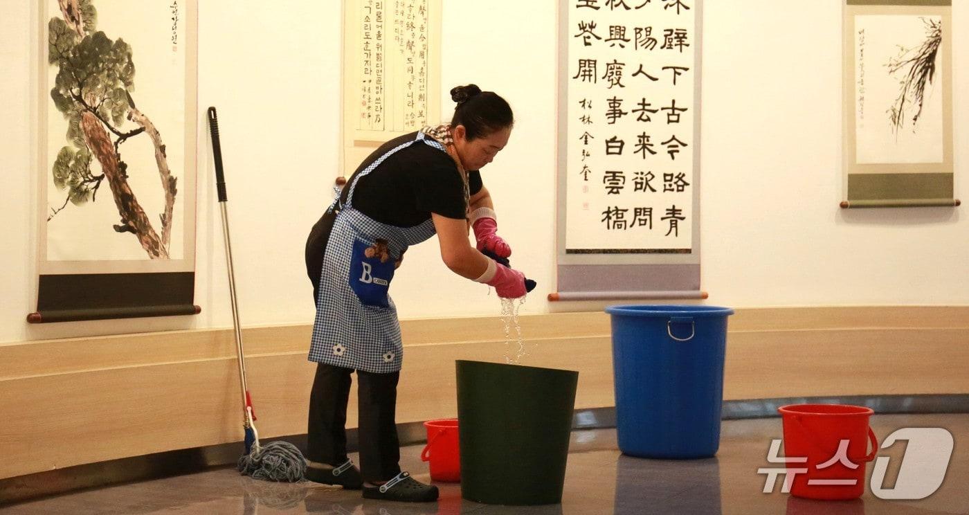 17일 제천시민회관 직원이 1층 전시관에서 양동이로 빗물을 받고 있다. 직원이 젖은 수건을 짜고 있다.2025.7.17./뉴스1 ⓒ News1 손도언 기자 