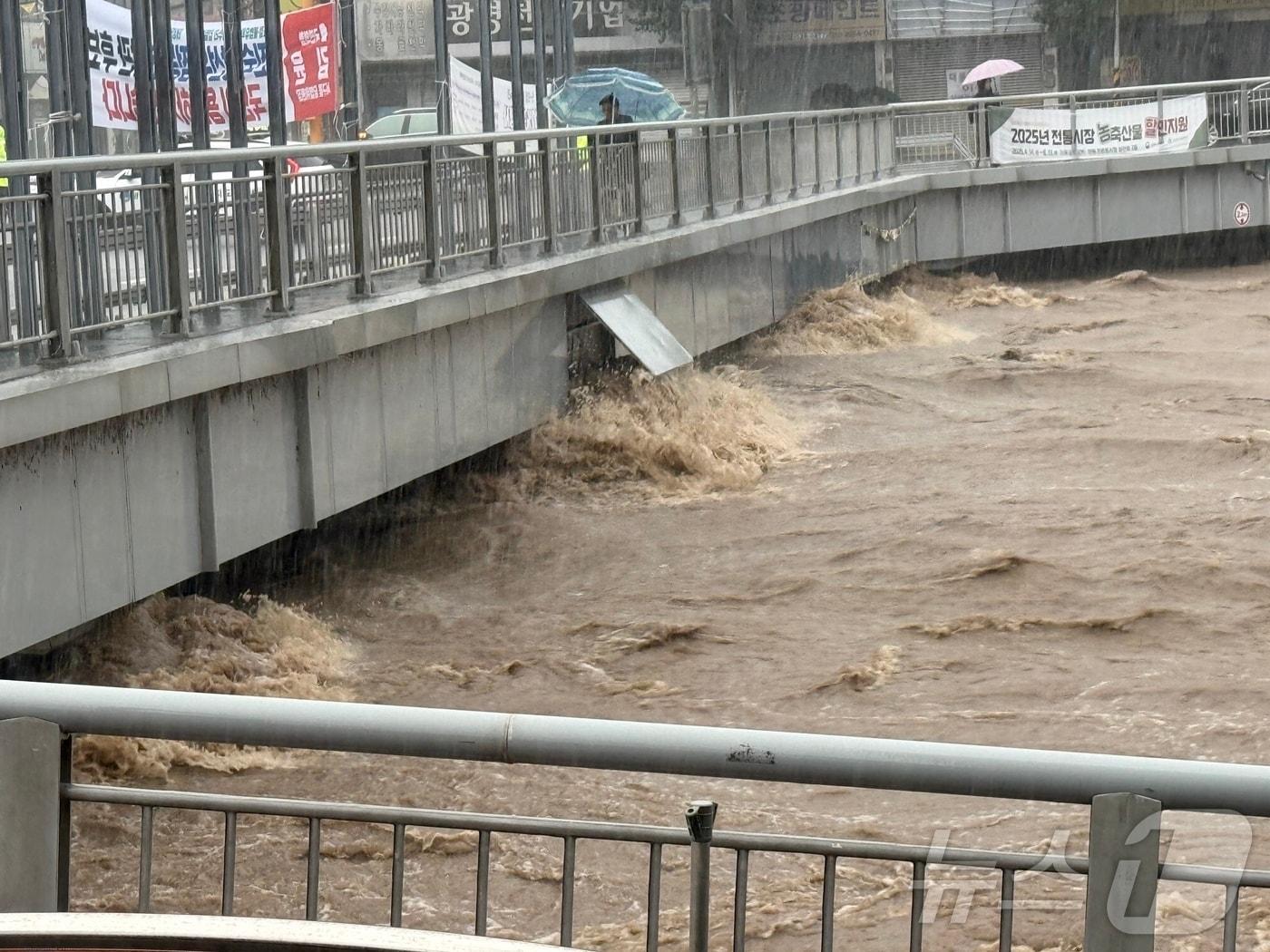본문 이미지 - 17일 이어진 집중호우로 광주천을 가로지르는 태평교가 범람 직전에 놓여 있다. 이에 따라 광주 서구는 양동복개상가 인근 상인과 일대 주민들에게 대피 명령을 내렸다. 닭전길과 수산시장, 복개상가를 비롯해 양동시장 전체 점포 수는 1000개 이상이다. 2025.7.17/뉴스1 ⓒ News1 김태성 기자