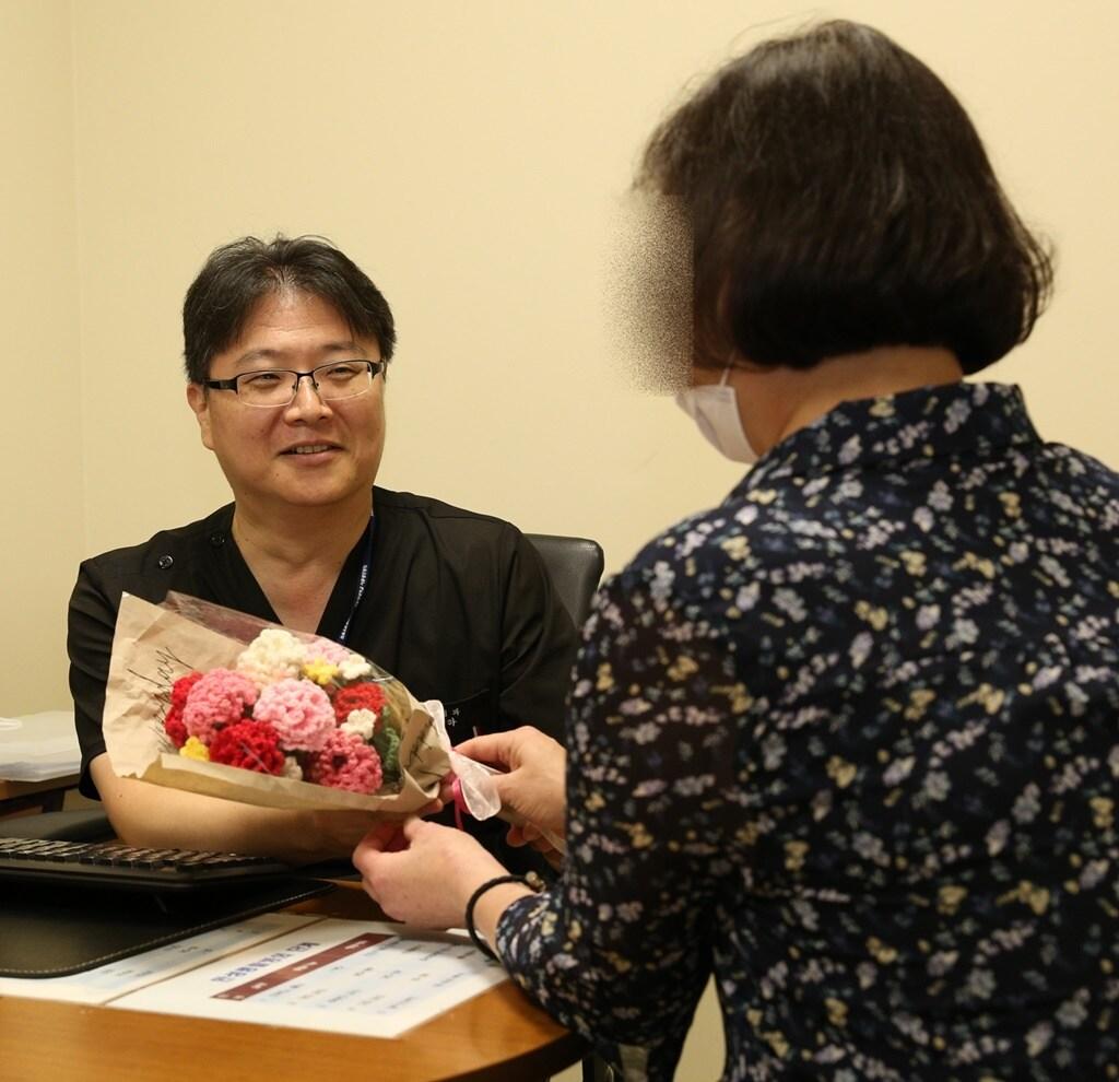 본문 이미지 - 50대 말기 신부전 환자가 고도 감작으로 재이식이 어려운 힘든 상황을 이겨내고 두 번째 신장이식 수술로 건강을 되찾고, 서울성모병원 신장내과 정병하 교수에게 뜨개질로 만든 카네이션 꽃다발을 전하고 있다(서울성모병원 제공)