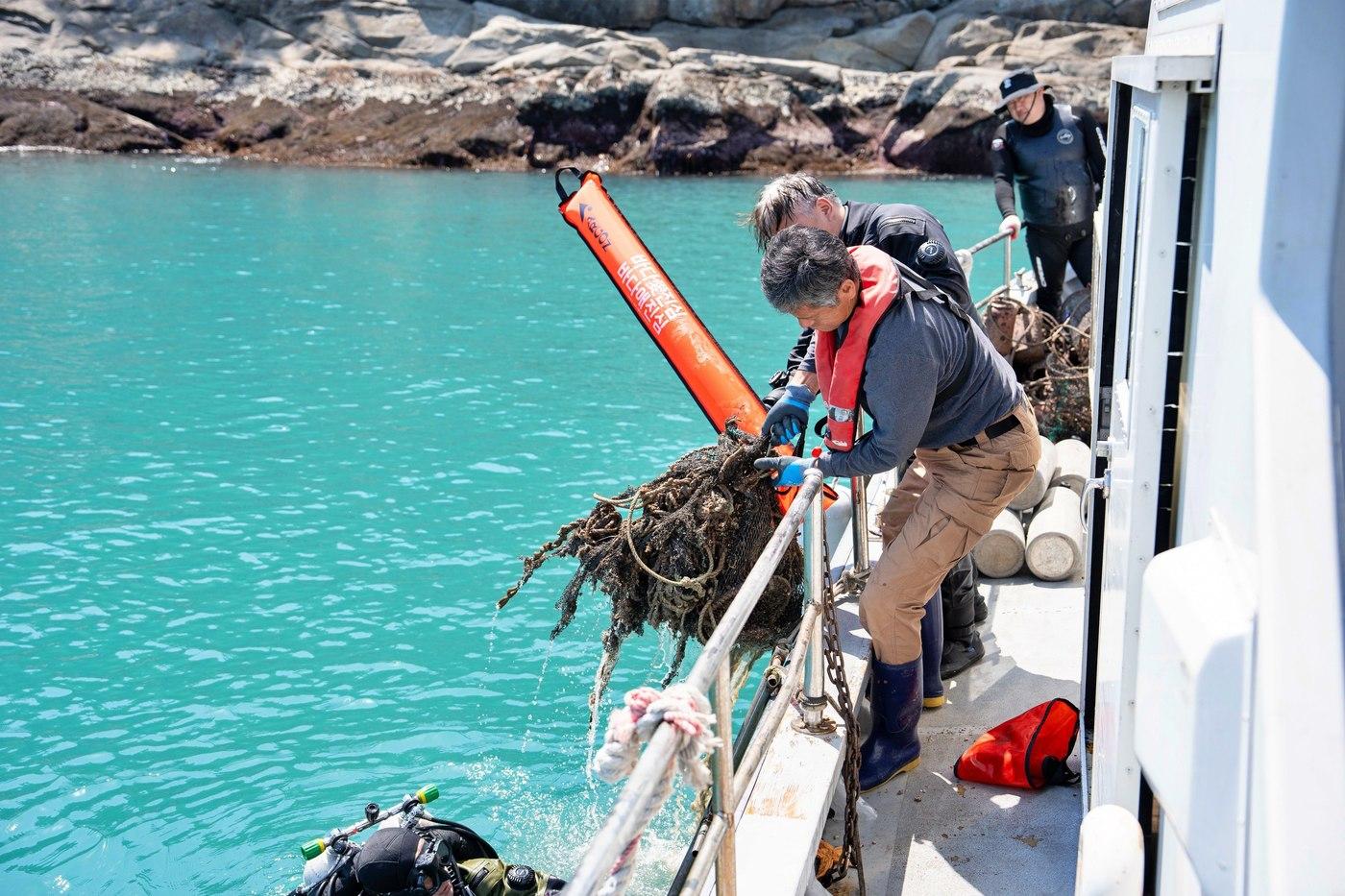 지난 17일 전라남도 여수시 돌산 진목방파제 연안에서 전문 스쿠버가 바다 속에서 수거한 폐그물을 끌어올리고 있다(롯데쇼핑 제공).
