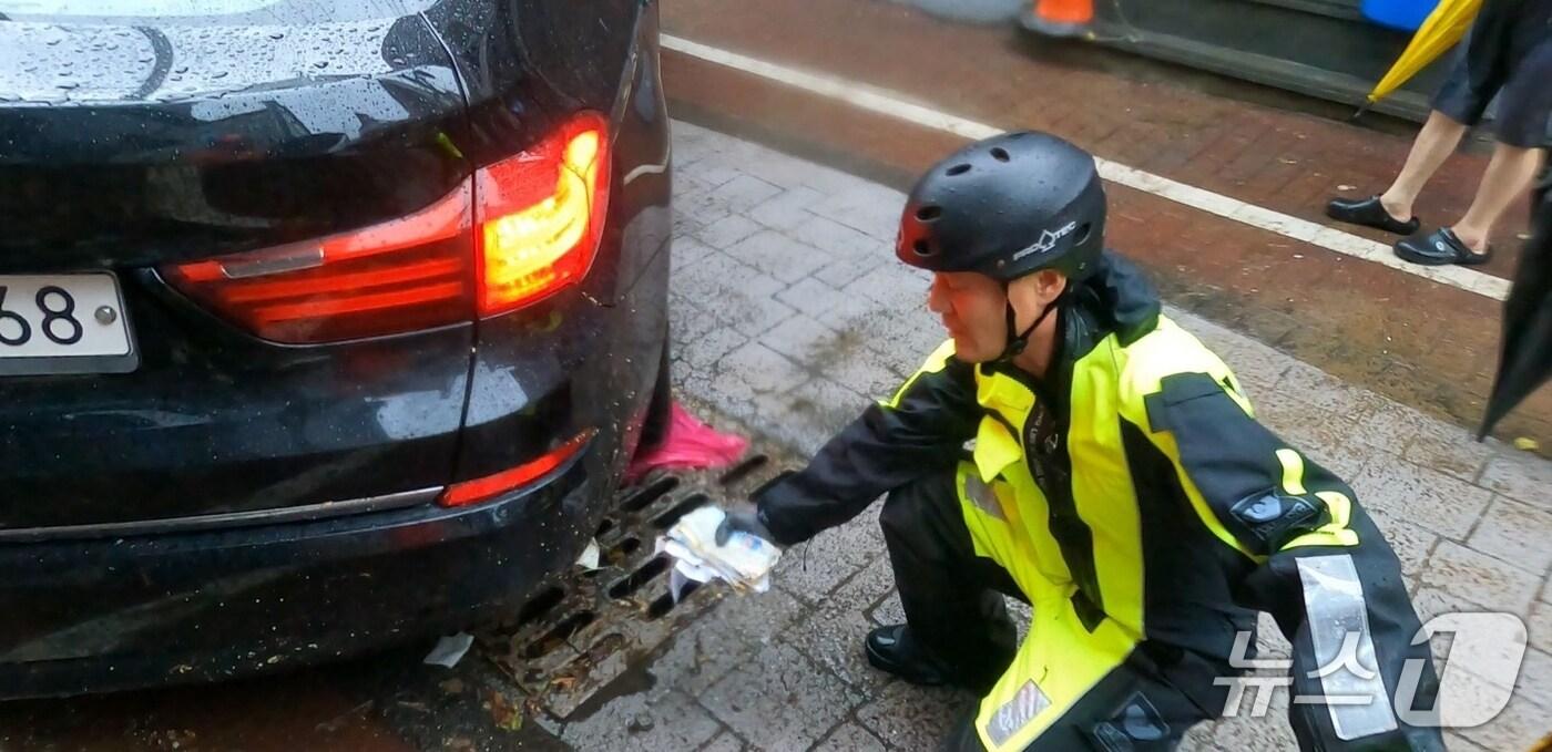 지난 17일 낮 12시 30분쯤 광주 북구 중흥동 전남대 정문 도로에서 침수차량 배수작업하던 박선홍 소방위가 유실된 현금봉투를 발견한 모습.&#40;광주 북부소방 제공. 재판매 및 DB 금지&#41;