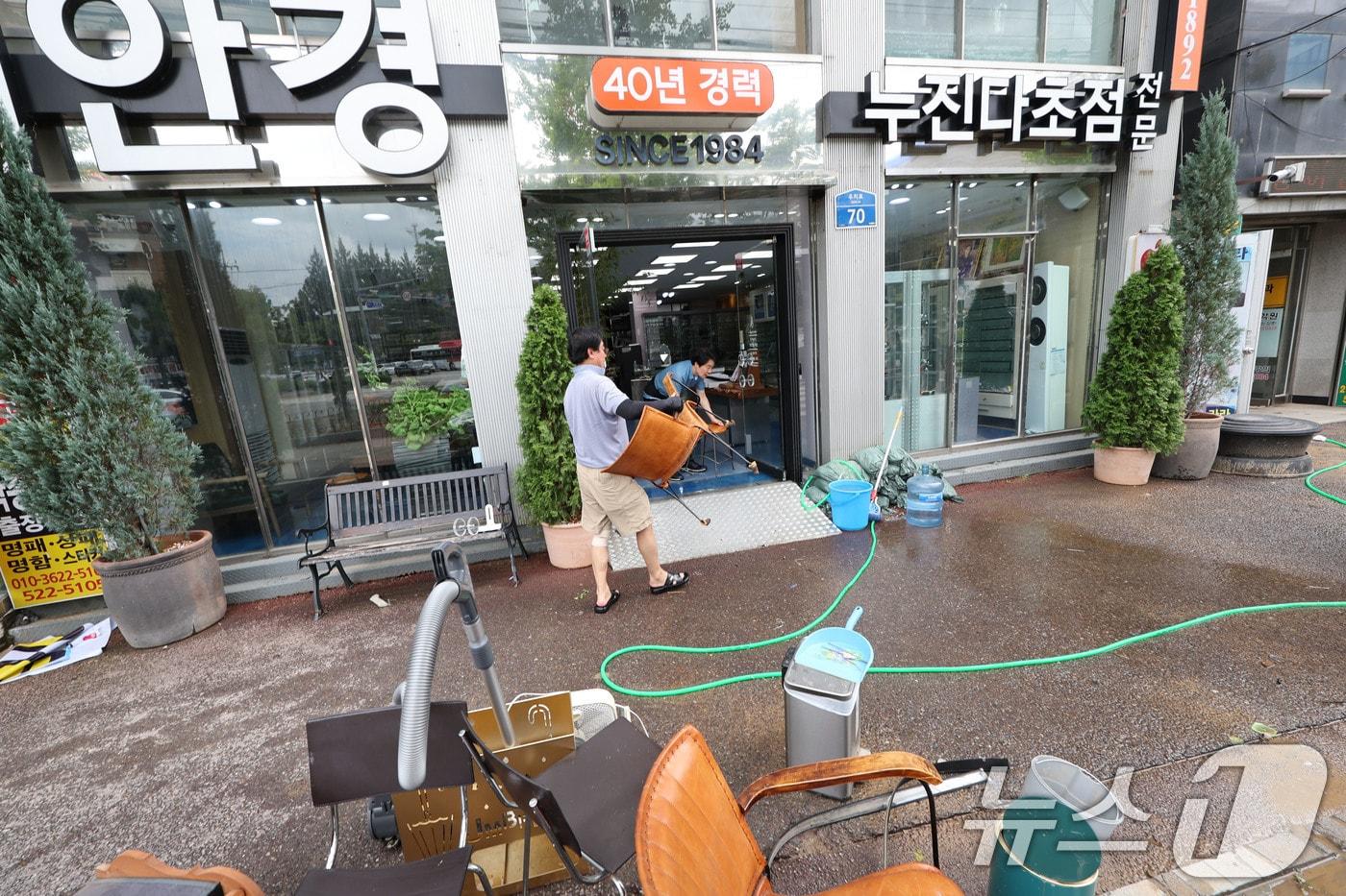 18일 광주 북구 용봉동 전남대 후문 일대가 전날 내린 폭우로 침수돼 한 안경상가의 상인이 물에 젖은 의자를 닦은 후 옮기고 있다. 2025.7.18/뉴스1 ⓒ News1 박지현 기자