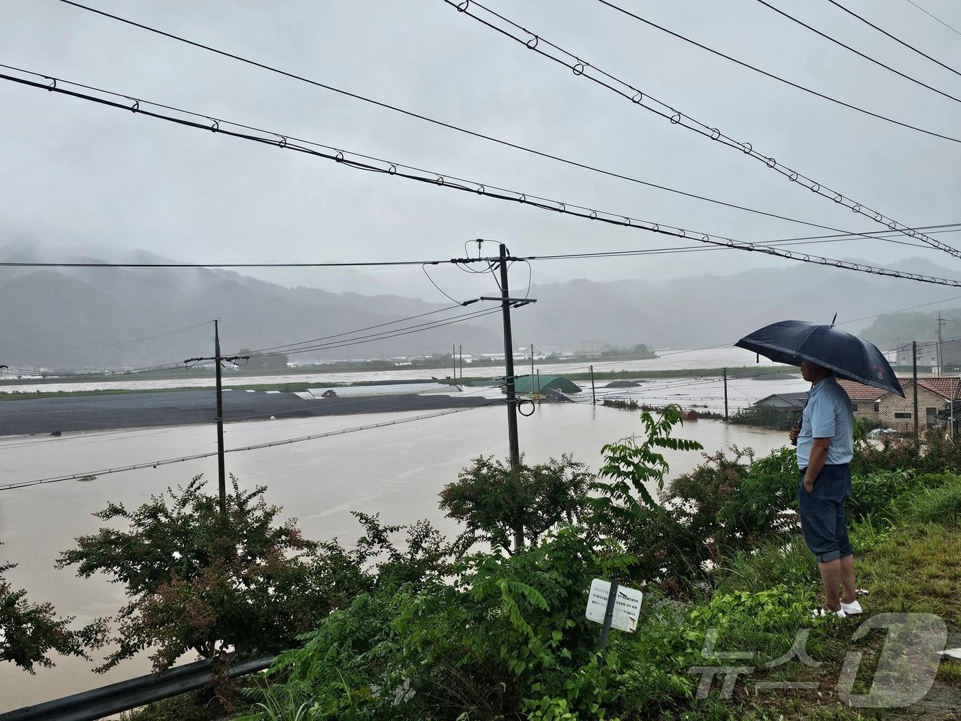 본문 이미지 - 19일 경남 산청 생비량면에서 한 주민이 집중호우로 인해 물에 잠긴 마을을 바라보고 있다. 2025.7.19/뉴스1. ⓒ News1 한송학 기자
