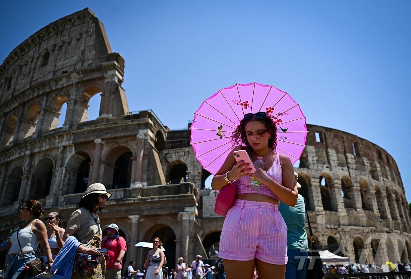 2025년 7월 1일, 로마 콜로세움 인근에서 한 여성이 무더운 여름날 햇볕을 피하기 위해 우산을 들고 있다.2025.07.01.ⓒ AFP=뉴스1
