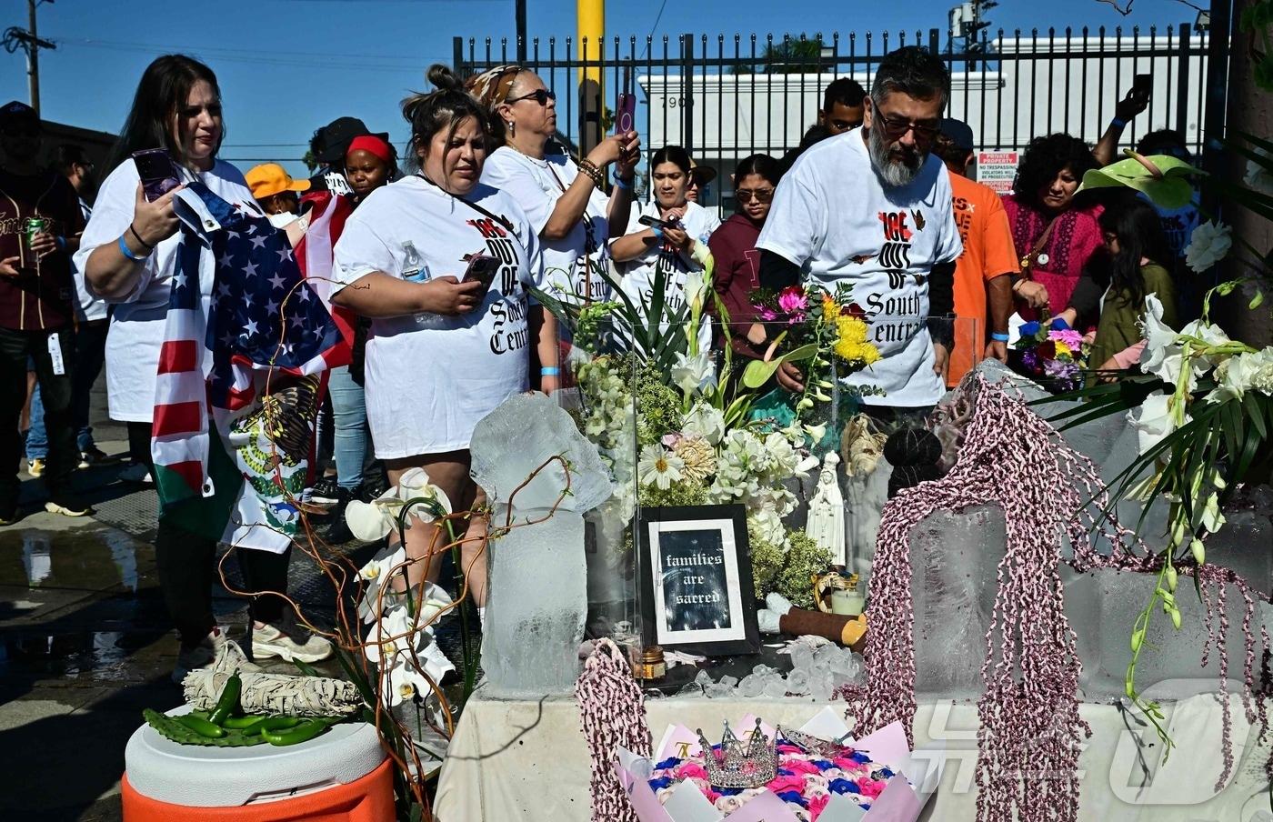 1일&#40;현지시간&#41; 캘리포니아주 로스앤젤레스에서 이민세관단속국&#40;ICE&#41;에 반대하는 시위대가 집회를 벌이는 가운데 한 남성이 임시 추모공간에 꽃을 놓고 있다. 로스앤젤레스와 미국 전역의 활동가들은 7월 1일을 맞아 ICE 급습의 표적이 된 이민자 커뮤니티에 연대의 표시로 &#39;ICE 병가&#40;Sick of ICE&#41;&#39;를 신청할 것을 촉구했다. 2025.7.1 ⓒ AFP=뉴스1