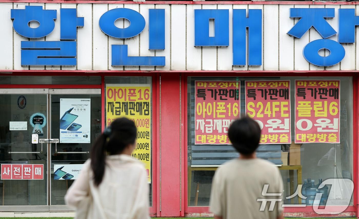 본문 이미지 - 서울 시내 한 핸드폰 매장앞에서 시민들이 이동하고 있다. 2025.7.20 ⓒ 뉴스1 황기선 기자
