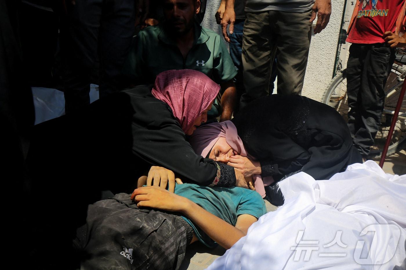 20일(현지시간) 팔레스타인 주민들이 가자 북부에서 구호품을 기다리다 이스라엘군의 총격으로 숨진 희생자를 끌어안고 있다. 2025.07.20. ⓒ 로이터=뉴스1 ⓒ News1 윤다정 기자