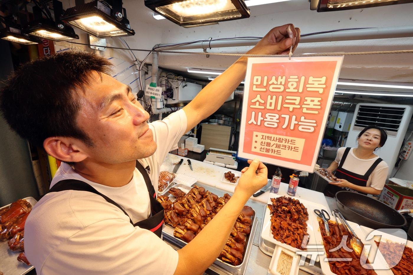 민생회복 소비쿠폰 1차 신청 첫 날인 21일 서울의 한 족발전문점에서 상인이 쿠폰 사용 관련 안내문을 붙이고 있다. 2025.7.21/뉴스1 ⓒ News1 황기선 기자