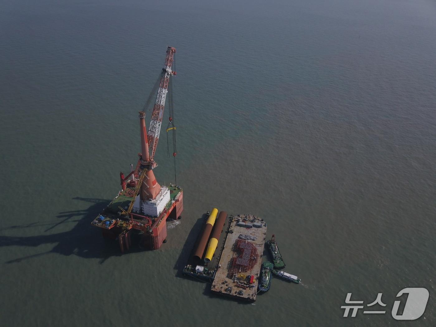 본문 이미지 - 전남 영광군 낙월면 인근 해역에서 진행 중인 ‘영광 낙월 해상풍력 프로젝트’ 현장. GS엔텍이 제작한 해상풍력 하부구조물 ‘모노파일’이 바다 위로 옮겨져 설치되고 있다.(GS그룹 제공)