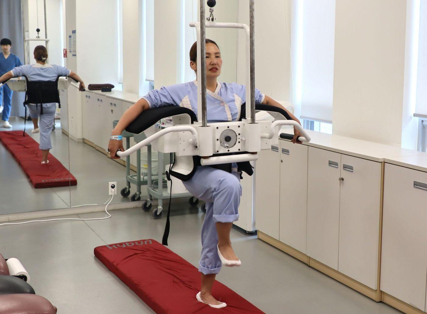 본문 이미지 - 자생한방병원 의료진이 나랑체첵 씨의 경추와 팔꿈치, 발등에 동작침을 놓은 뒤 스스로 걷도록 유도하는 동작침법을 시행하고 있다.&#40;자생한방병원 제공&#41;