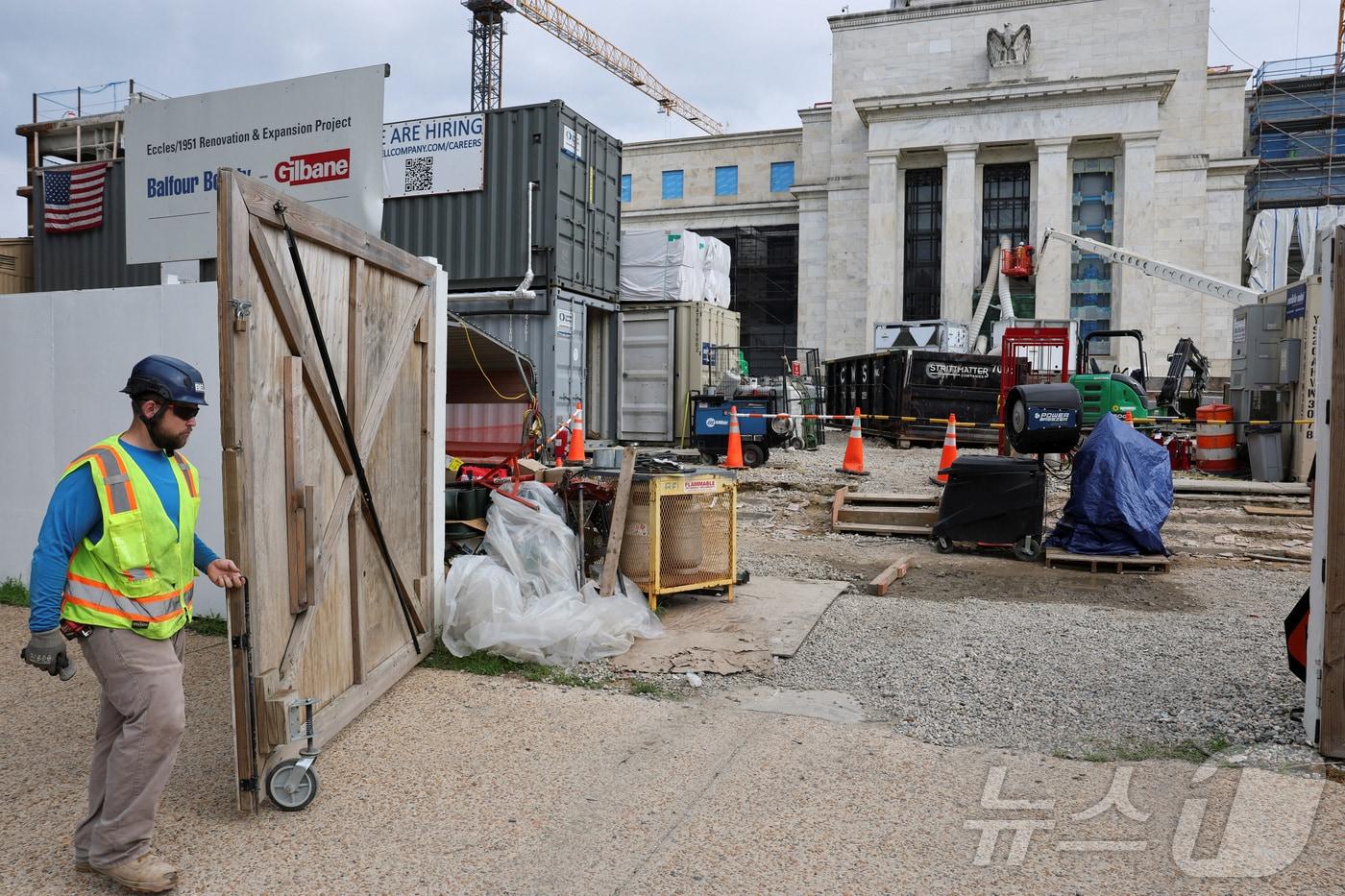 한 건설 노동자가 워싱턴 D.C.에 위치한 미국 연방준비제도 청사 공사장에서 입구 게이트를 닫고 있다. 2025.7.18 ⓒ 로이터=뉴스1