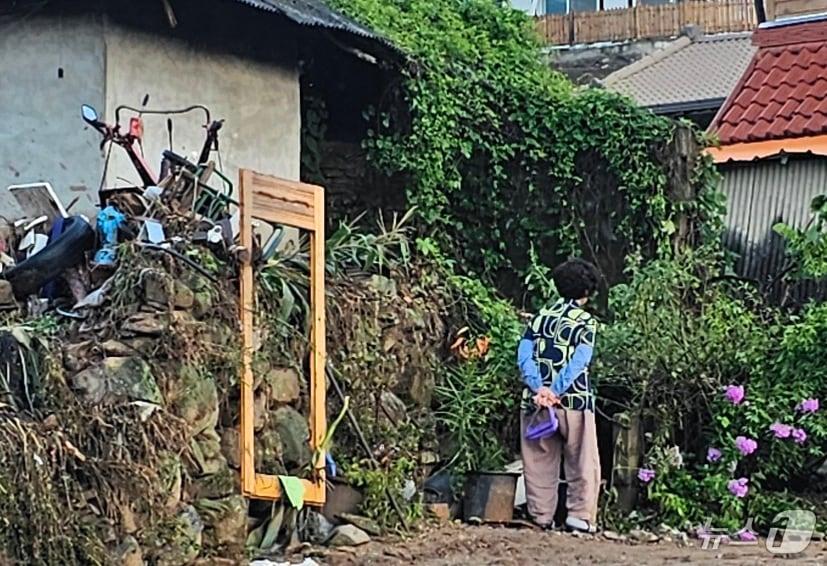 본문 이미지 - 22일 경남 산청군 율현마을 산사태 실종자의 아내 전인호 씨(74)가 자신의 집과 주변을 살펴보며 실종된 남편을 찾고 있다. 2025.7.22/뉴스1 ⓒ News1 한송학 기자