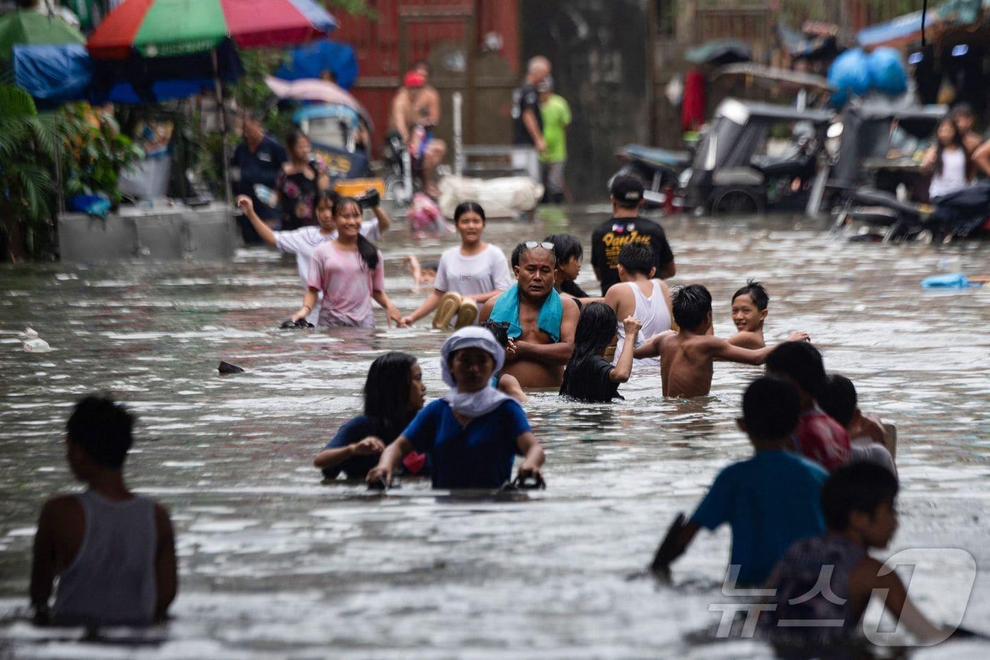 21일 태풍 위파의 영향으로 폭우와 홍수가 발생한 필리핀 마닐라에서 시민들이 물에 잠긴 거리를 걸어서 이동하고 있다.2025.07.21. ⓒ AFP=뉴스1