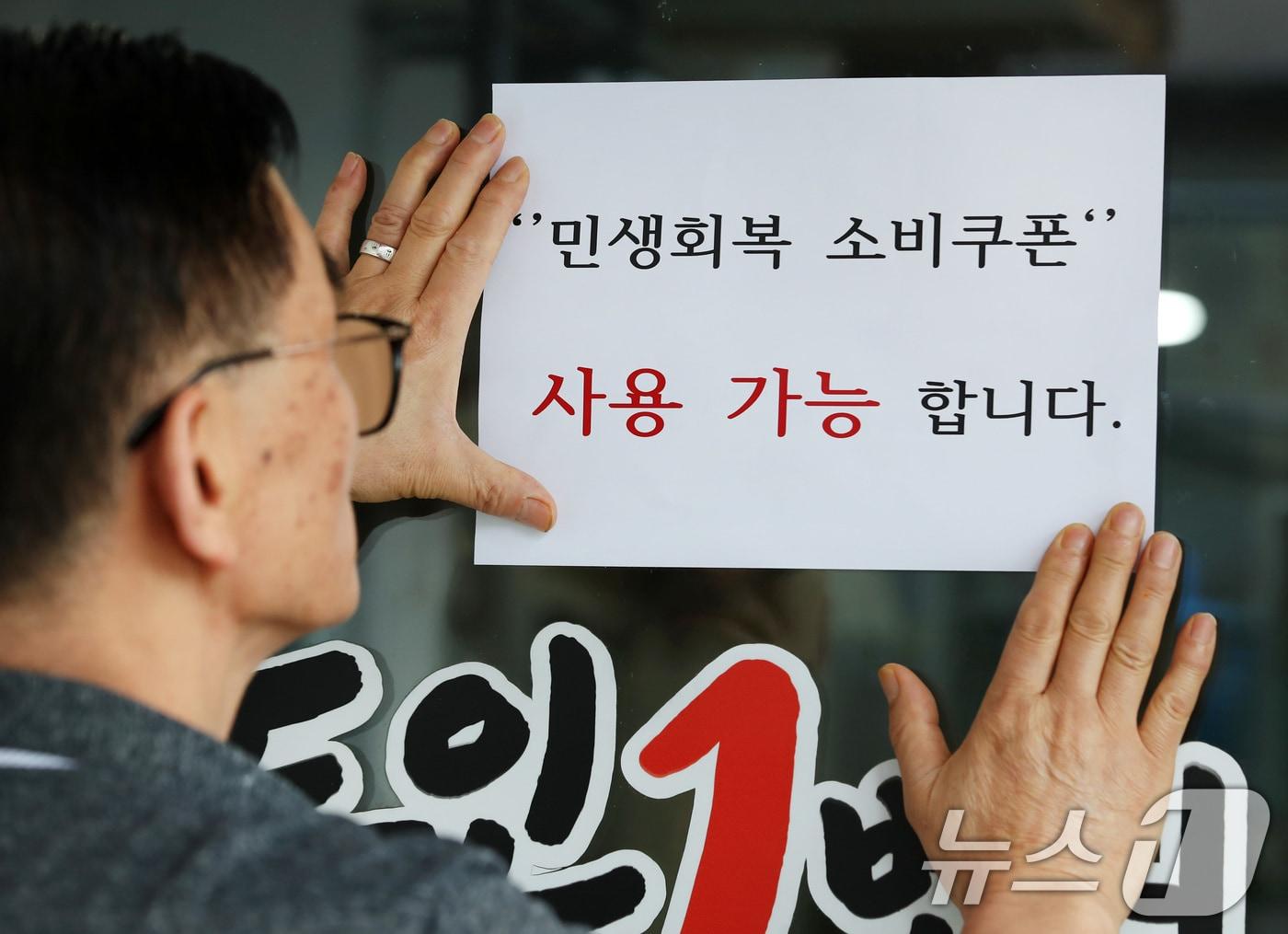 본문 이미지 - 22일 오후 대구 중구의 한 음식점 주인이 출입문에 민생회복 소비쿠폰 사용 가능 안내문을 붙이고 있다. 2025.7.22/뉴스1 ⓒ News1 공정식 기자
