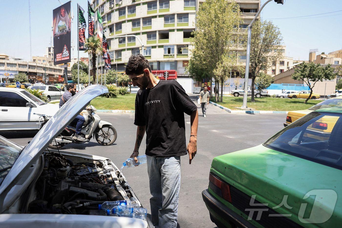 22일(현지시간) 이란 테헤란의 한 택시 운전사가 과열된 택시 엔진을 식히고 있다. 이란 기상청은 지난 19일 일부 지역의 기온이 섭씨 50도를 넘었다고 발표했다. 2025.07.22. ⓒ AFP=뉴스1 ⓒ News1 윤다정 기자