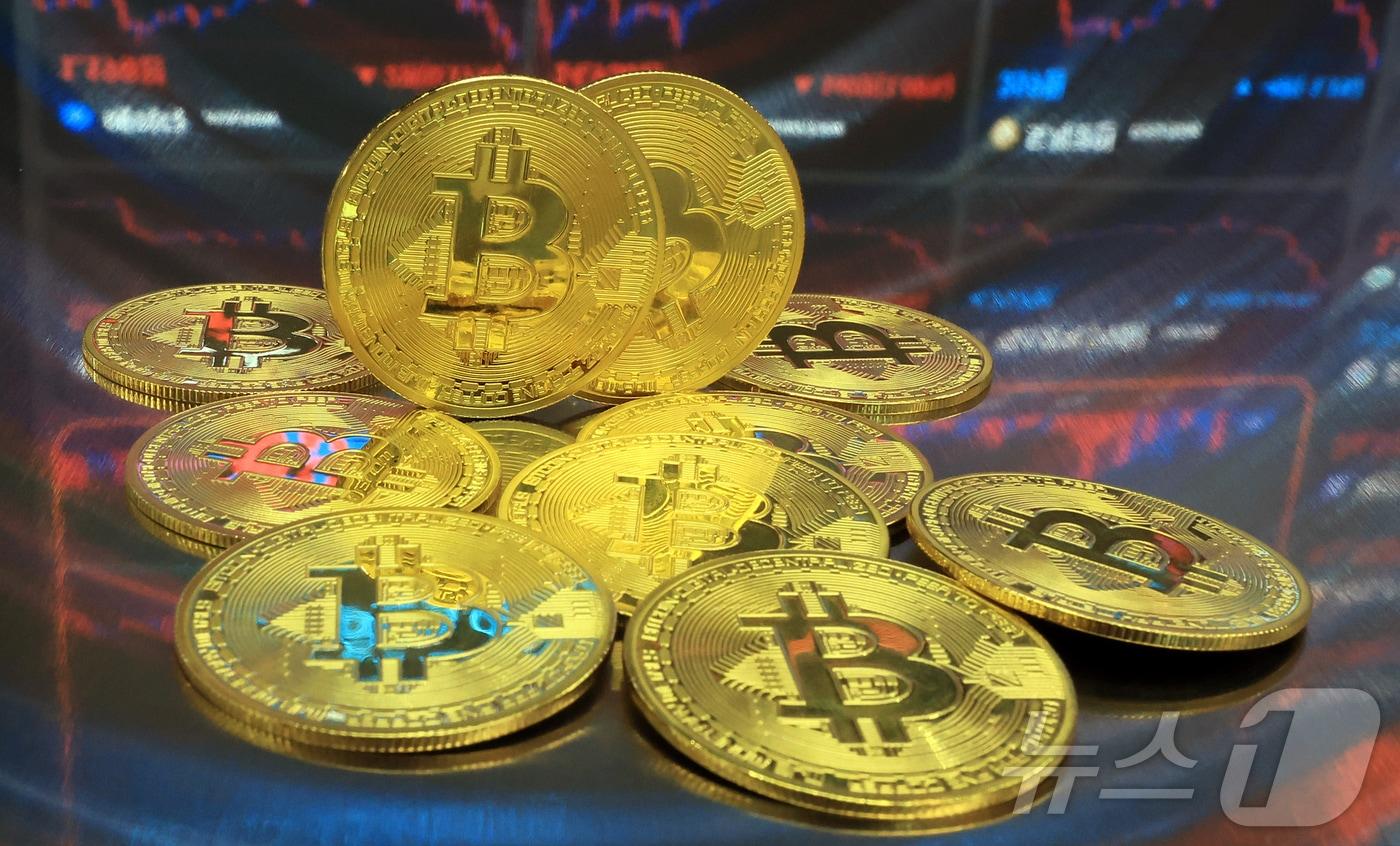 본문 이미지 - 지난해 7월  오후 서울 강남구 서초구 빗썸라운지 강남본점에서 비트코인 모형이 놓인 바닥에 코인 시세 그래프가 비치는 모습. 2025.7.23 ⓒ 뉴스1 김진환 기자