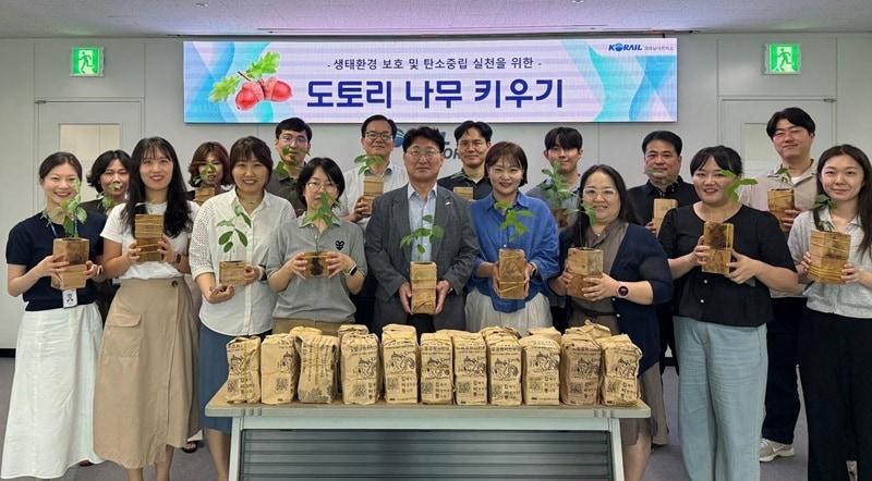 본문 이미지 - 코레일네트웍스 대표이사 전찬호&#40;앞줄 중앙&#41; 및 임직원들이 100일 동안 직접 기른 도토리 묘목을 들고 기념촬영을 진행하고 있다. / 사진=코레일네트웍스 제공
