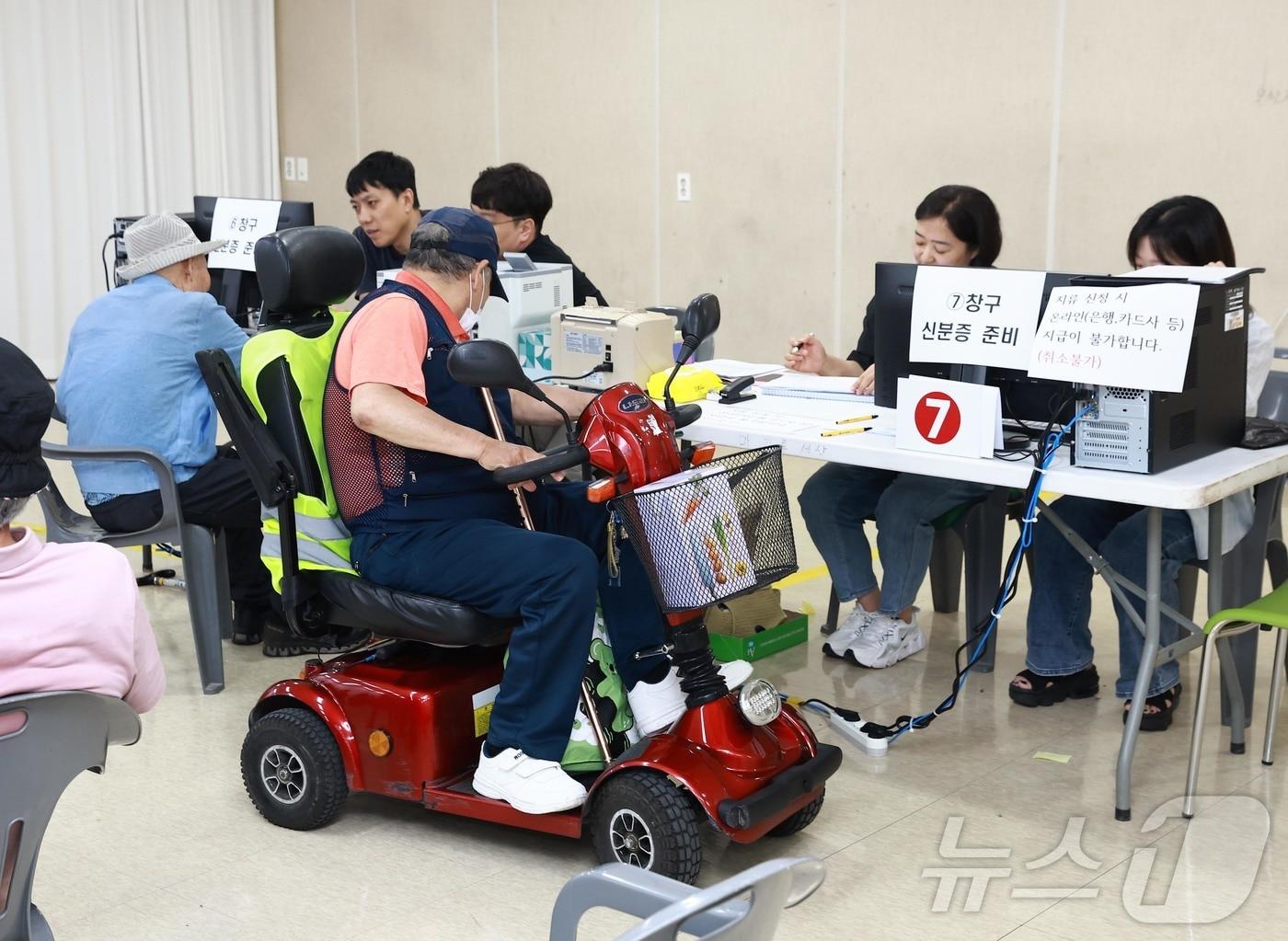 본문 이미지 - 전 국민을 대상으로 지원하는 민생회복 소비쿠폰 신청 사흘째인 23일 오전 전남 화순군 군민종합문화센터에 마련된 화순읍 접수창구에서 한 어르신이 전동스쿠터를 타고 쿠폰을 신청하고 있다.(화순군 제공, 재배포 및 DB 금지) /뉴스1