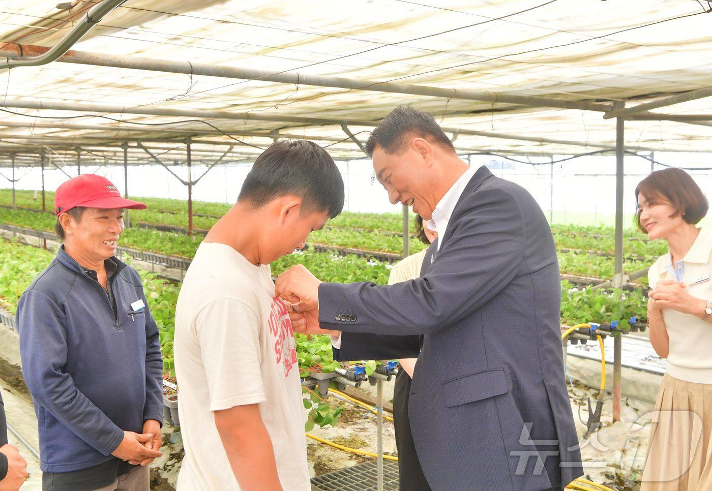 김한종 전남 장성군수가 외국인 계절근로자에 한글 이름 명찰을 달아주고 있다.(장성군 제공. 재배포 및 DB 금지)