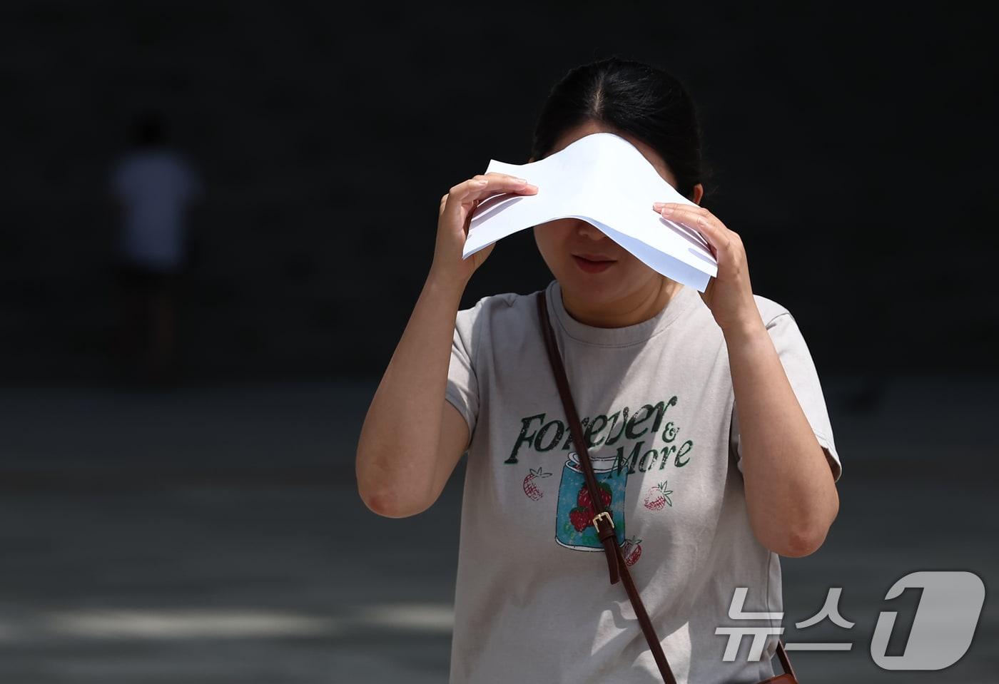 서울 전역에 폭염경보가 내려진 24일 서울 용산구 국립중앙박물관에서 시민이 종이로 뜨거운 햇빛을 가리고 있다. 2025.7.24/뉴스1 ⓒ News1 김민지 기자