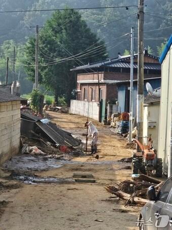본문 이미지 - 합천군 가회면 구평마을의 한 주민이 23일 집 앞 배구수의 이물질을 걷어내고 있다. 2025.7.23/뉴스1 한송학기자