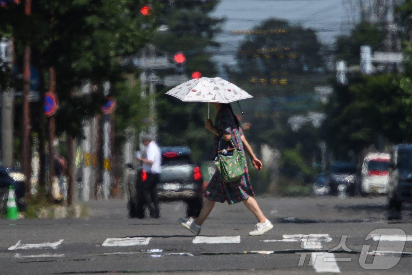 24일 폭염이 찾아온 일본 홋카이도 오비히로에서 한 행인이 양산을 쓰고 횡단보도를 건너고 있다. 2025.7.24 ⓒ AFP=뉴스1 ⓒ News1 강민경 기자