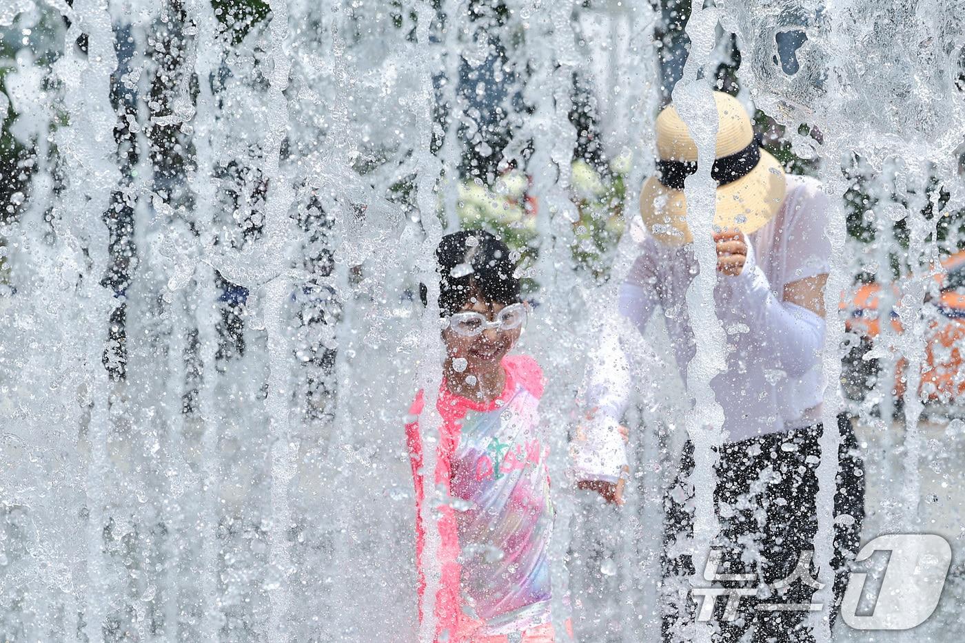 전국 대부분 지역에 폭염 경보가 발효된 25일 서울 광화문광장 바닥분수에서 한 어린이가 보호자와 함께 물놀이를 하며 더위를 식히고 있다. 기상청은 토요일인 오는 25일에는 서울 낮 최고기온이 38도까지 올라갈 것으로 예보했다. 2025.7.25/뉴스1 ⓒ News1 신웅수 기자