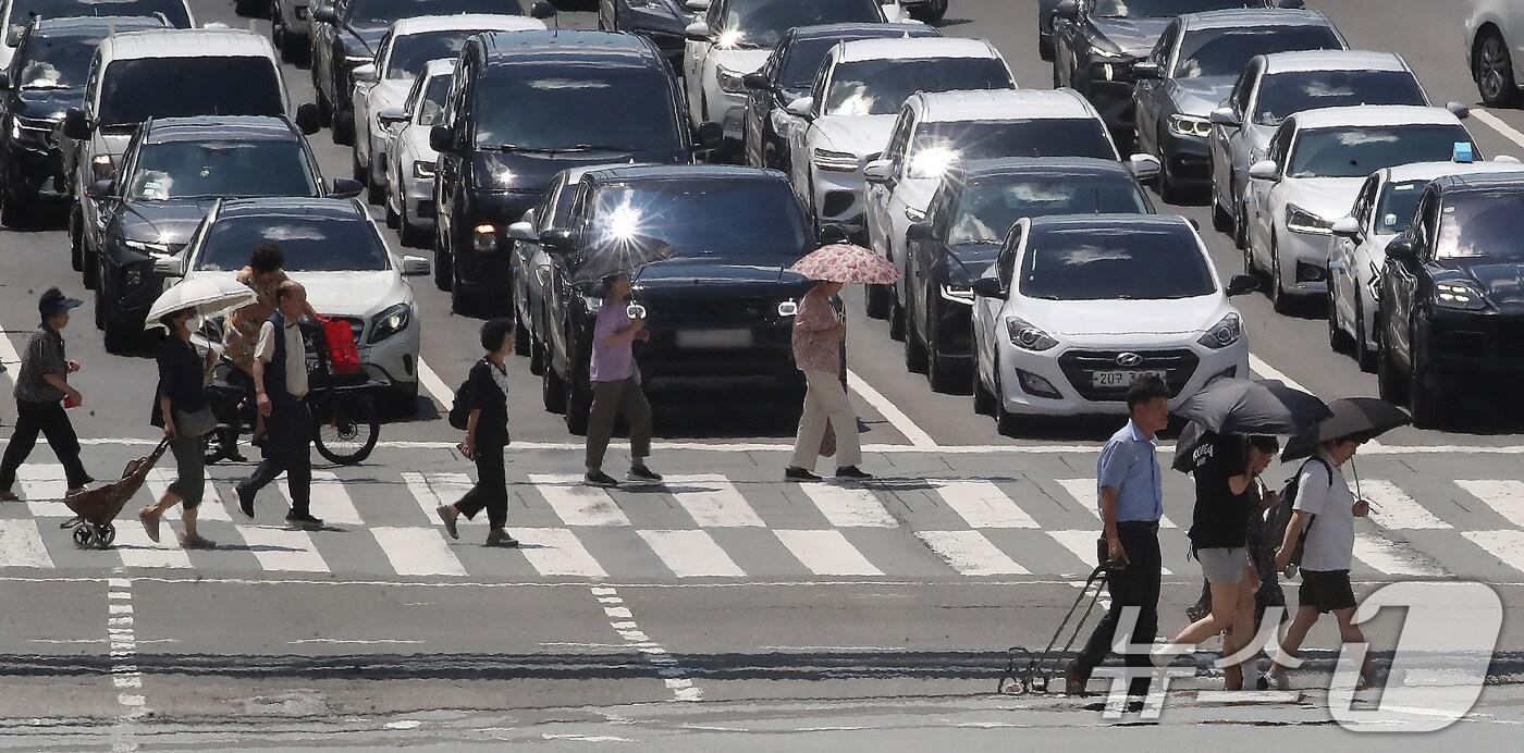 폭염이 연일 계속되는 25일 오후 대구 중구 달구벌대로에서 양산을 쓴 시민들이 아지랑이가 피어오르는 도로를 건너고 있다. 2025.7.25/뉴스1 ⓒ News1 공정식 기자