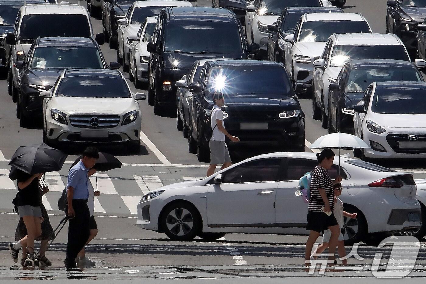 폭염이 연일 계속되는 25일 오후 대구 중구 달구벌대로에서 양산을 쓴 시민들이 아지랑이가 피어오르는 도로를 건너고 있다. 2025.7.25/뉴스1 ⓒ News1 공정식 기자