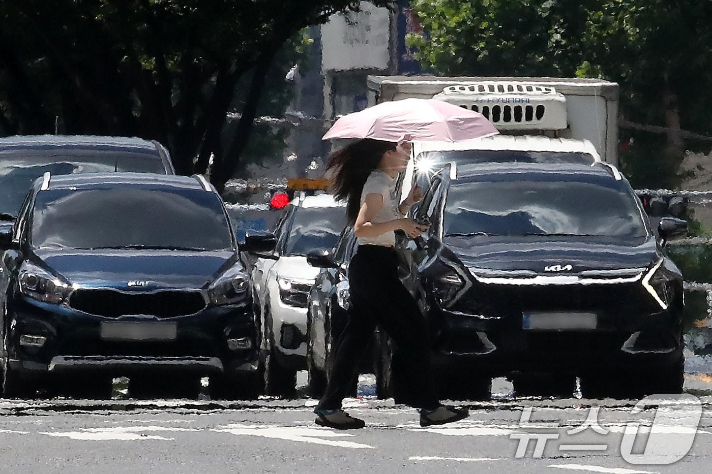 폭염이 연일 계속되는 25일 오후 대구 중구 달구벌대로에서 양산을 쓴 시민이 아지랑이가 피어오르는 도로를 건너고 있다. 2025.7.25/뉴스1 ⓒ News1 공정식 기자
