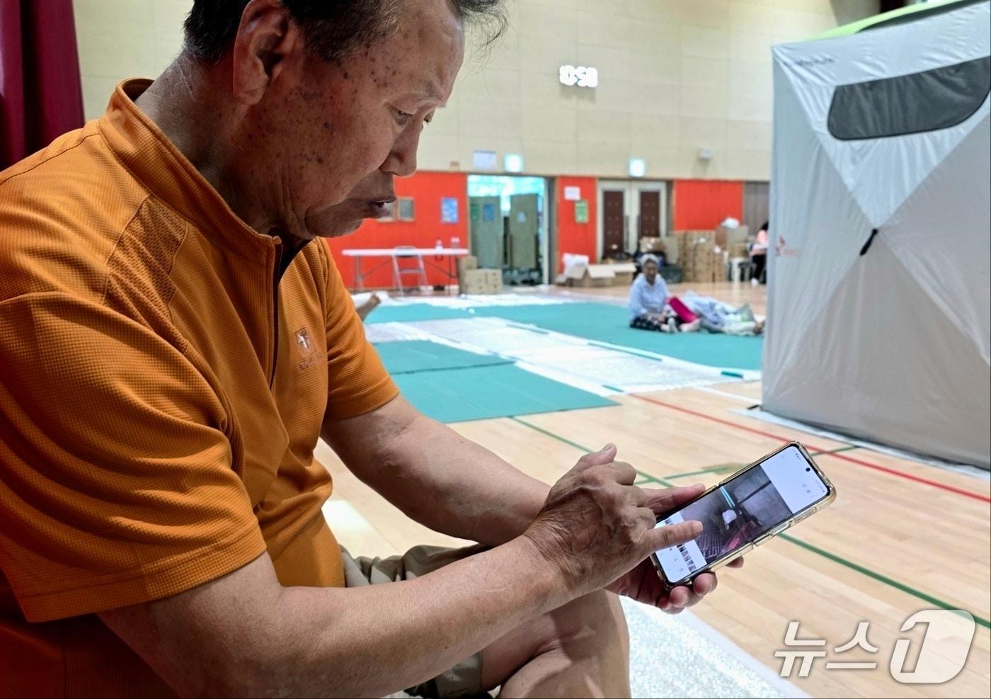 26일 아산 염티초등학교에서 대피 생활 중인 전모 씨가 침수 피해 당시 촬영한 사진을 보고 있다. 2025.7.26. /뉴스1ⓒNews1 이시우 기자
